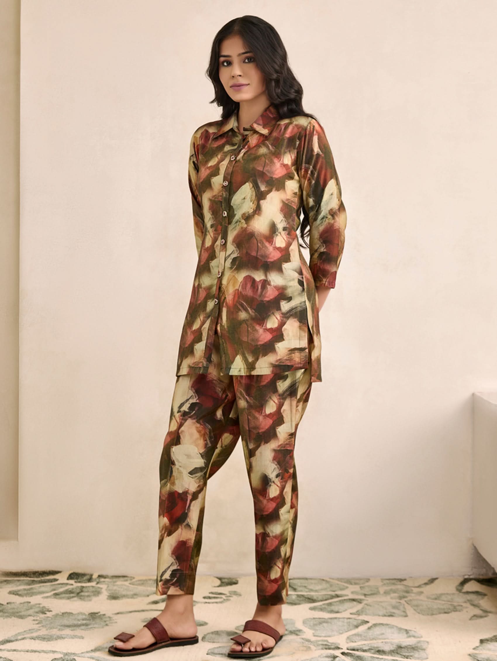 Woman wearing a floral outfit standing in a room with a neutral background