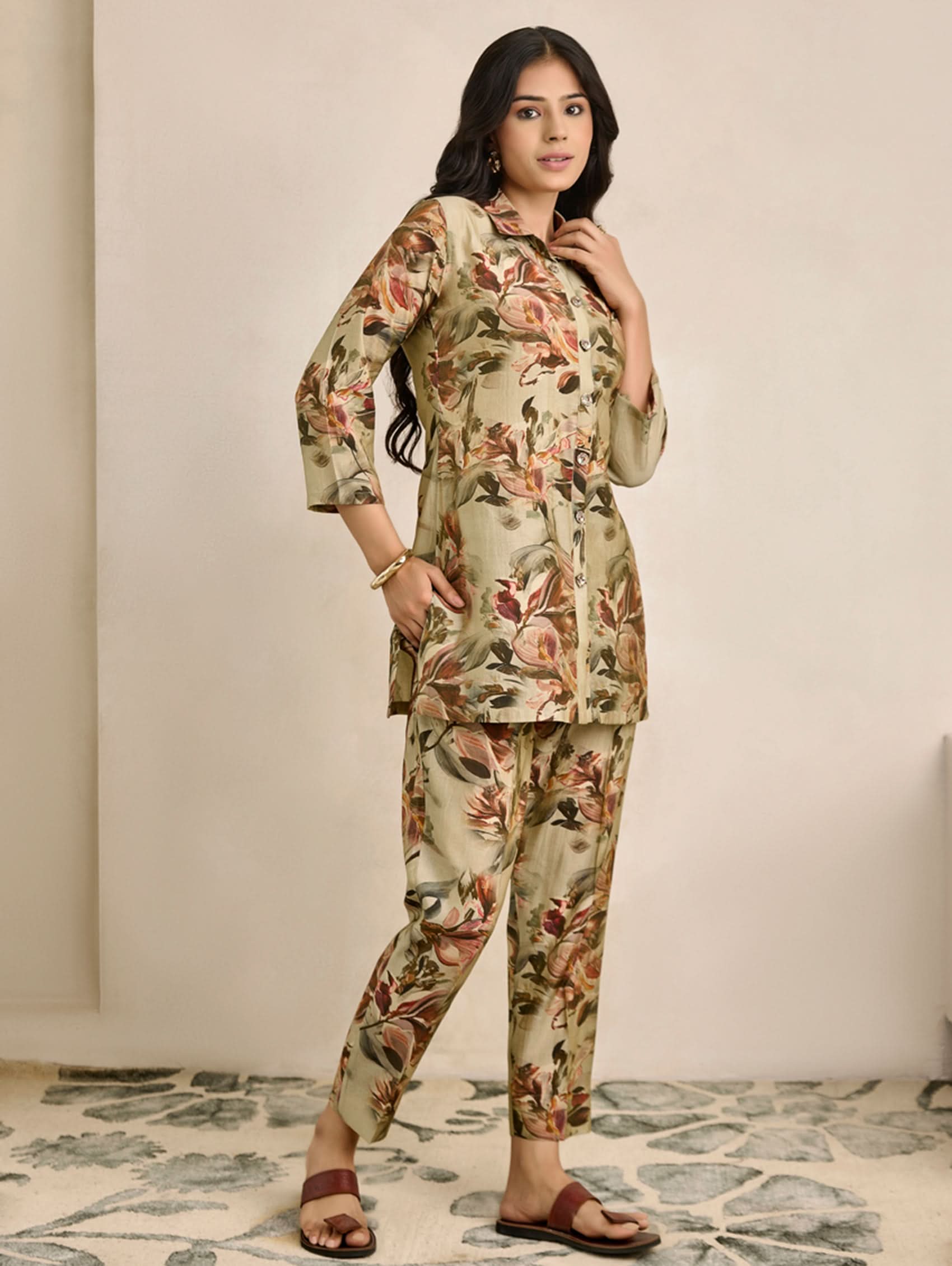 Woman wearing a floral outfit standing against a neutral background