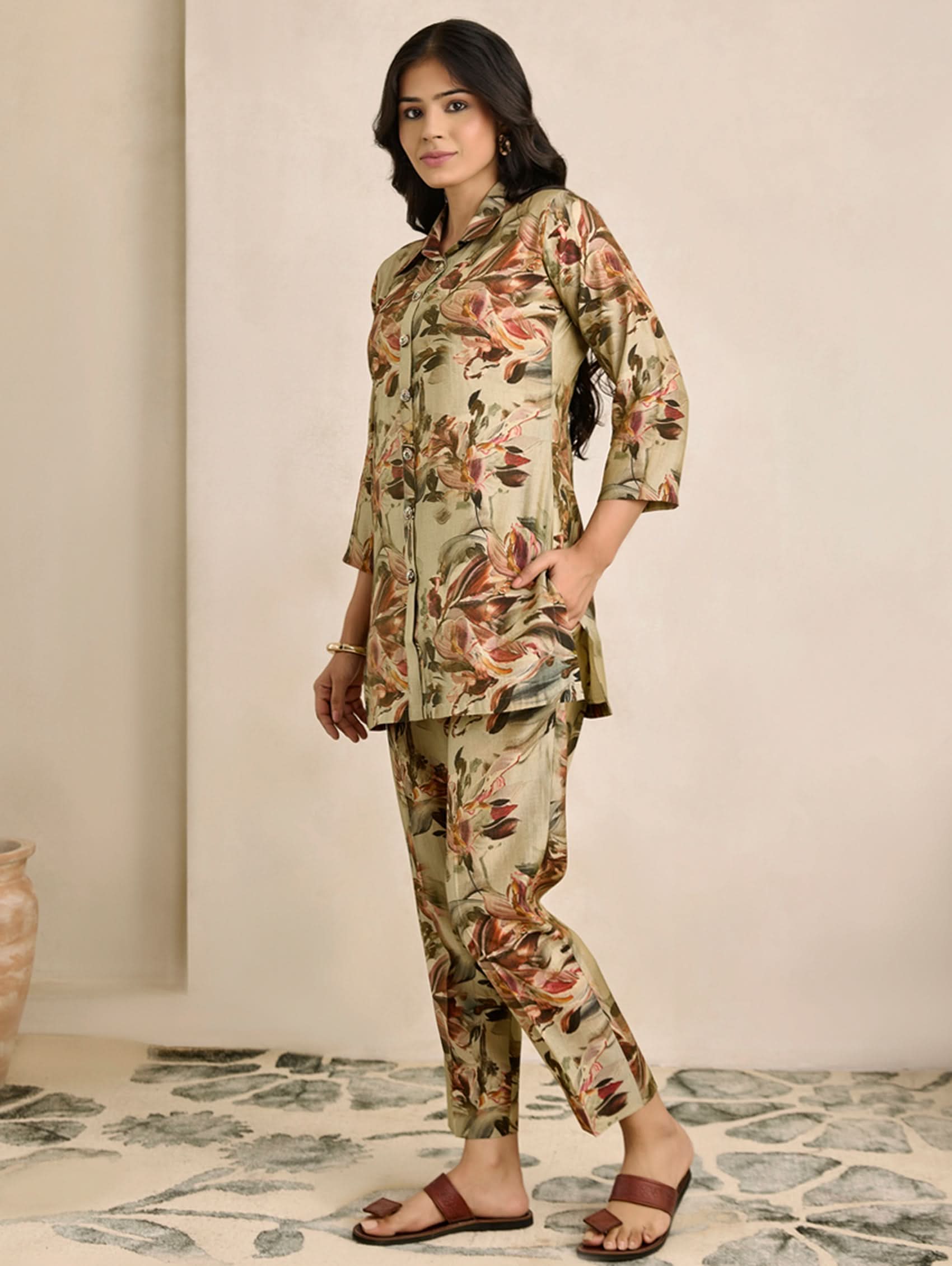 Woman wearing a floral outfit standing in a room with a neutral background