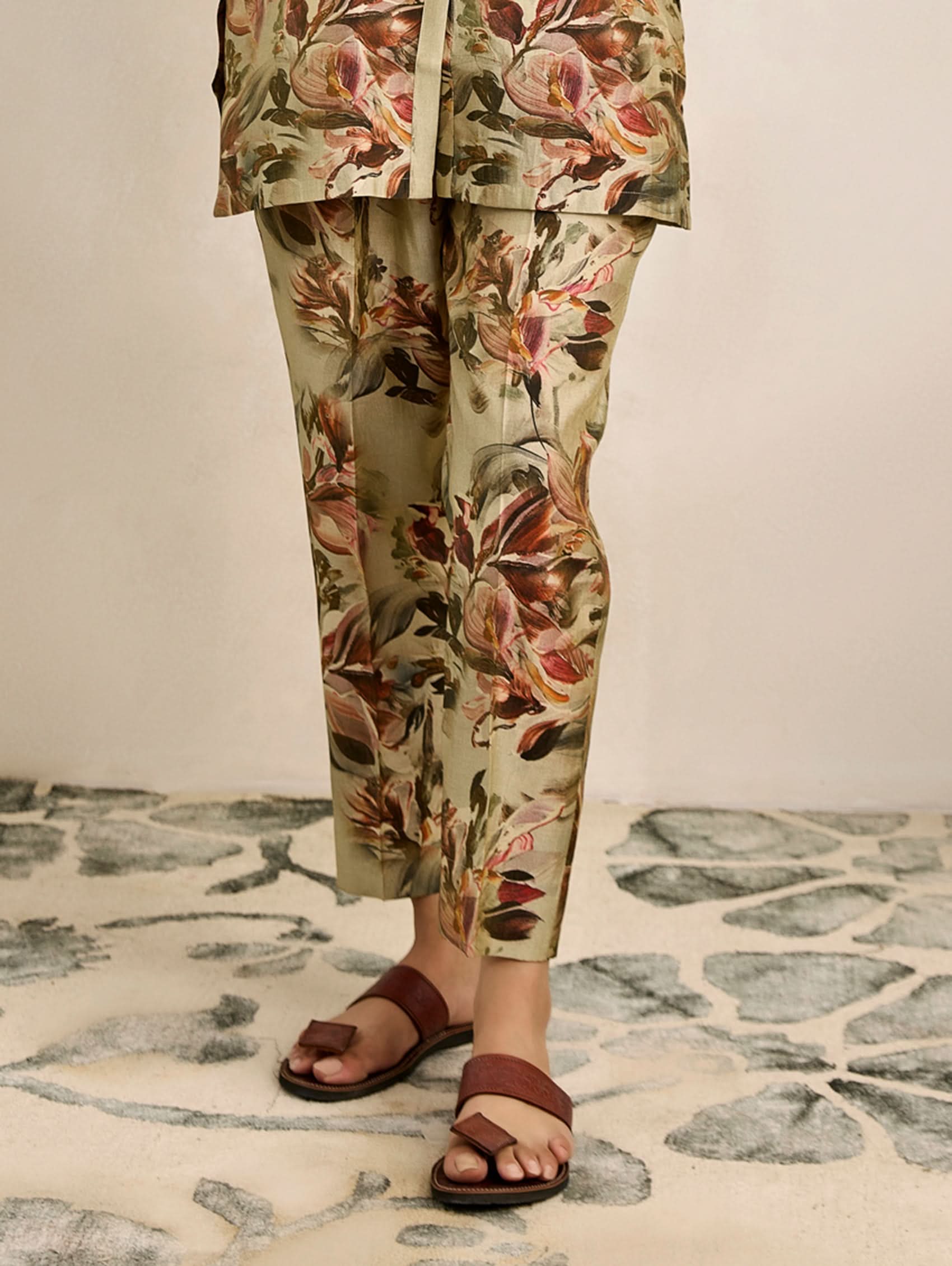 Person wearing floral pants and sandals on a stone floor.
