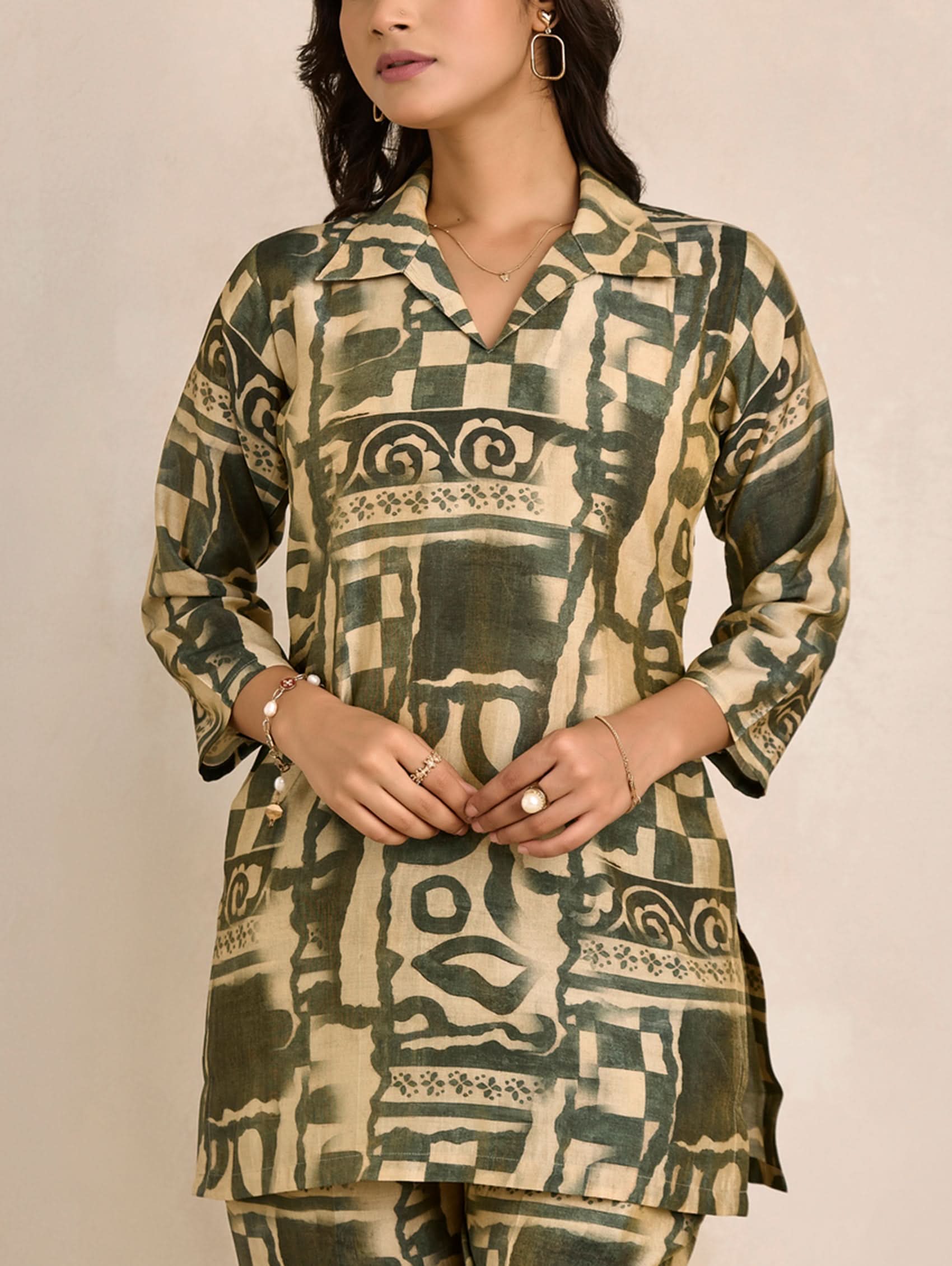 Woman wearing a patterned green and beige kurta against a plain background