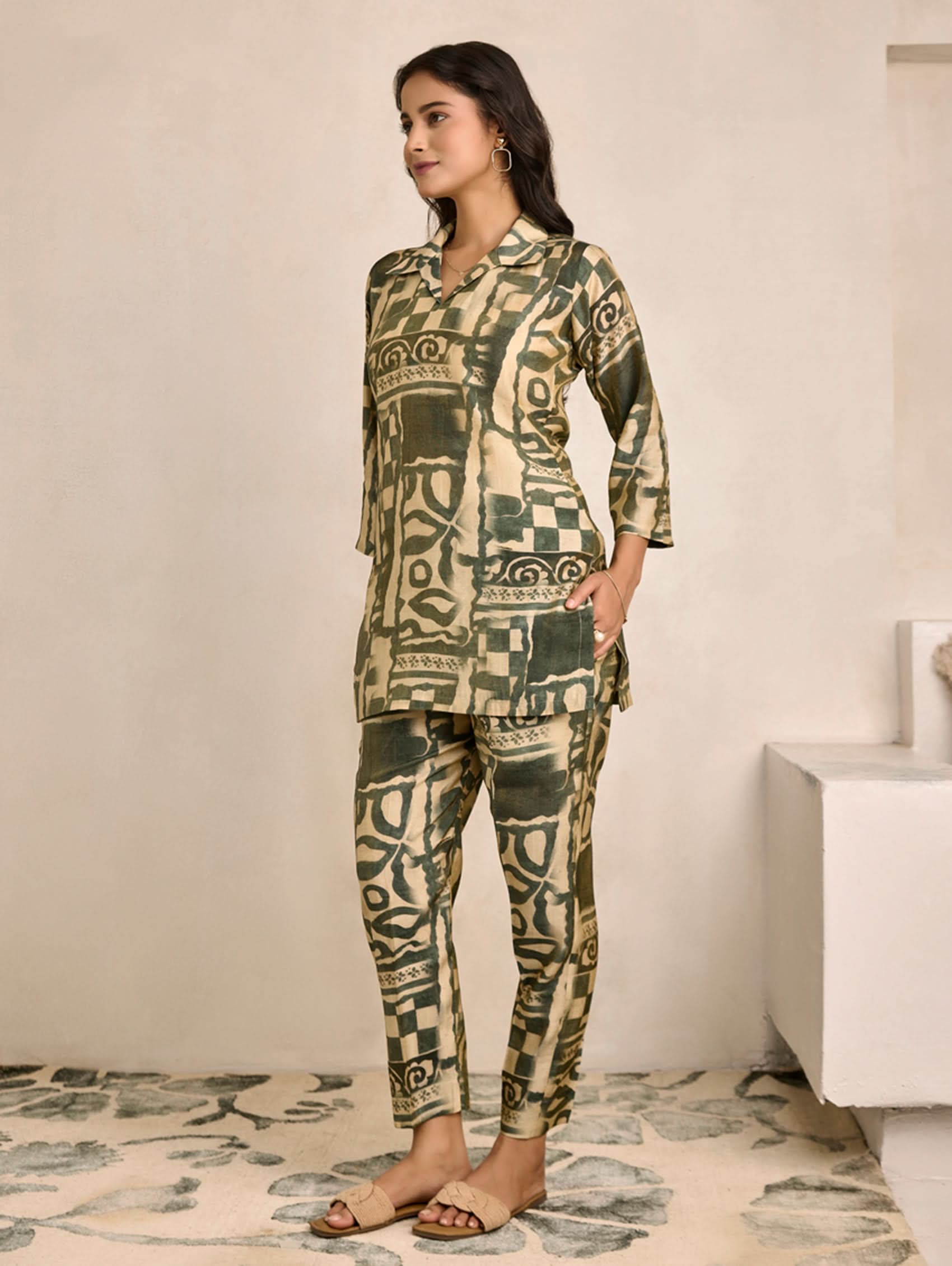 Woman wearing a patterned outfit standing in a room with a neutral background