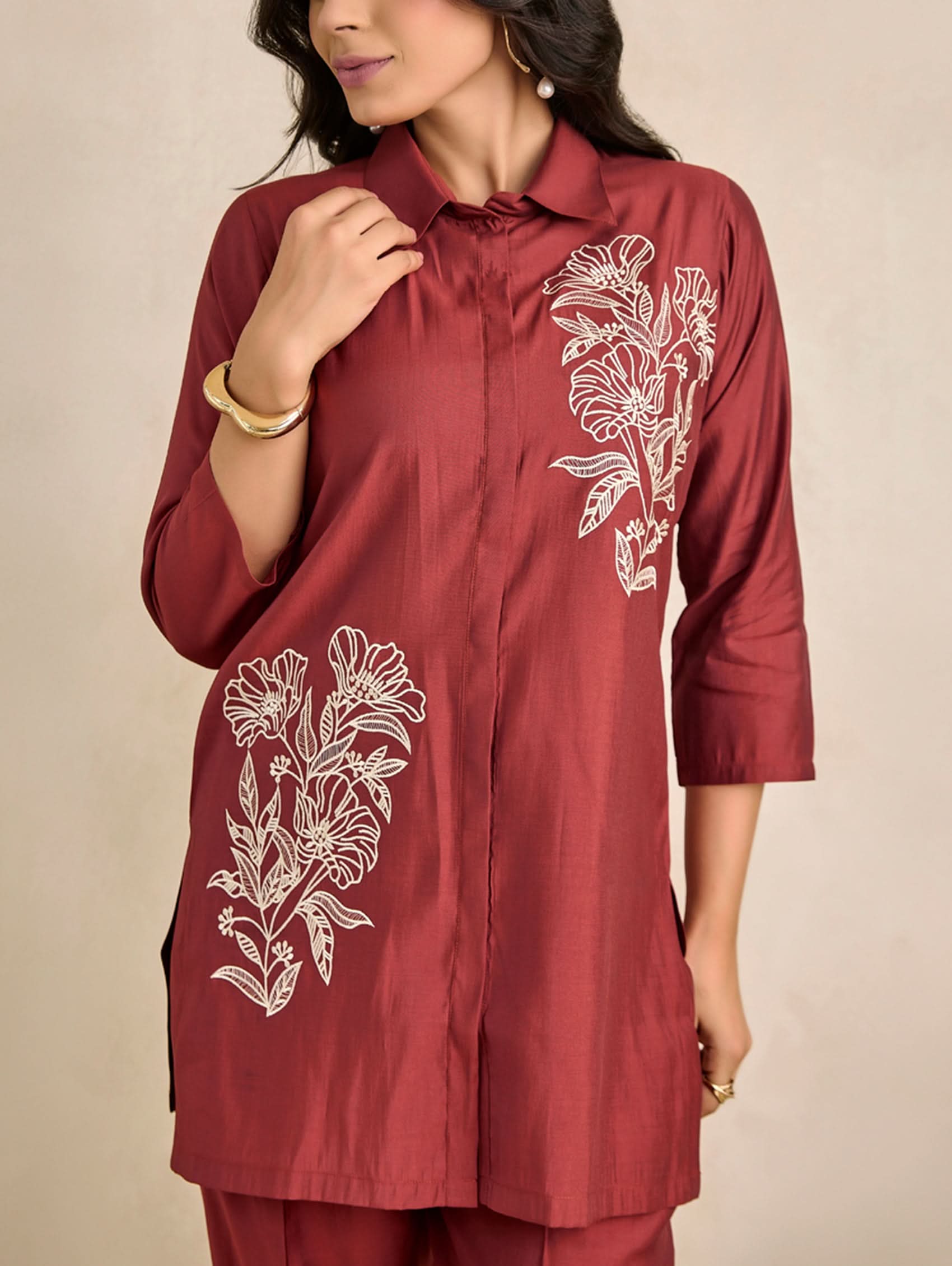 Red embroidered shirt worn by a person on a beige background