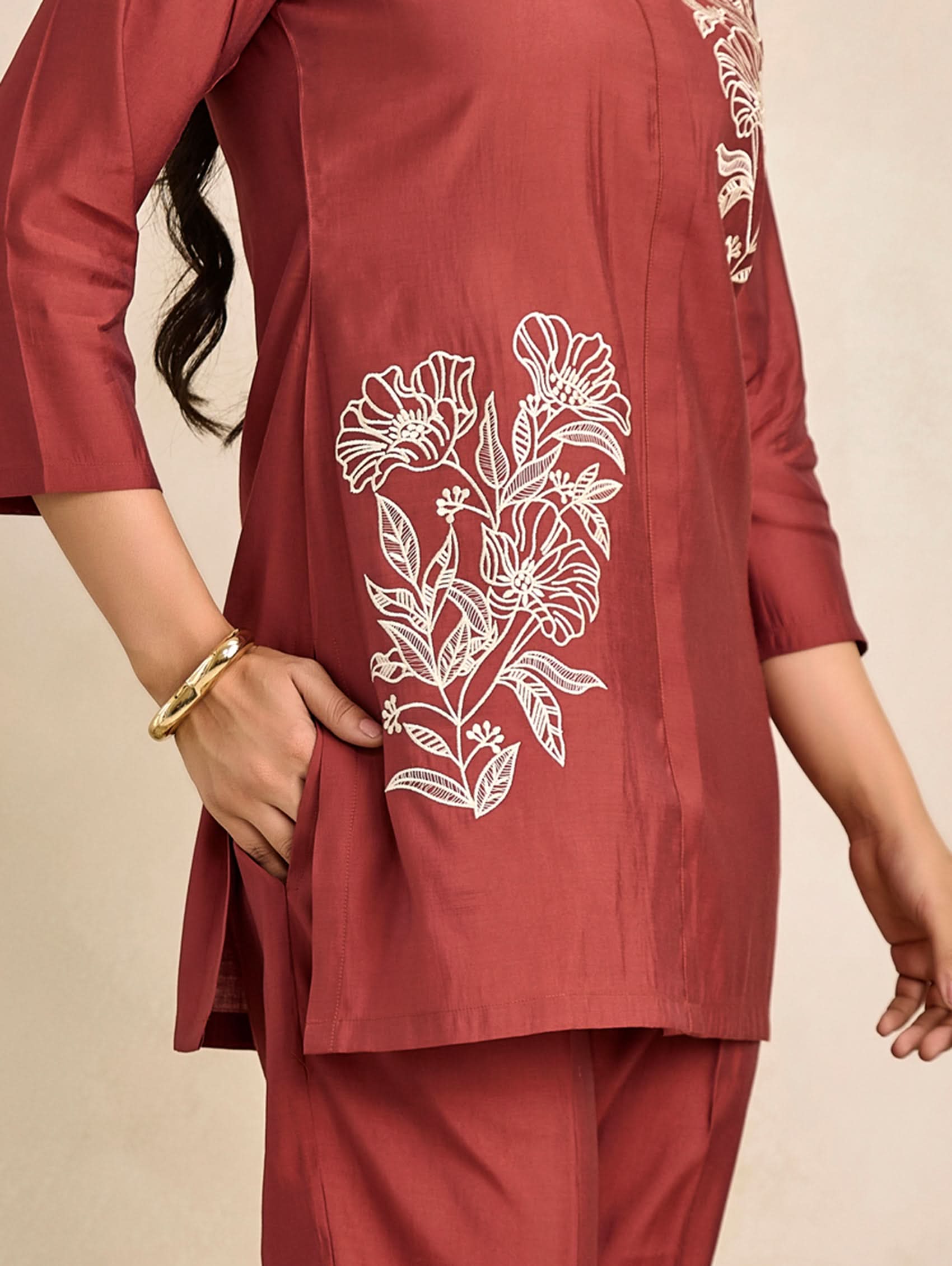 Red outfit with floral embroidery on a beige background