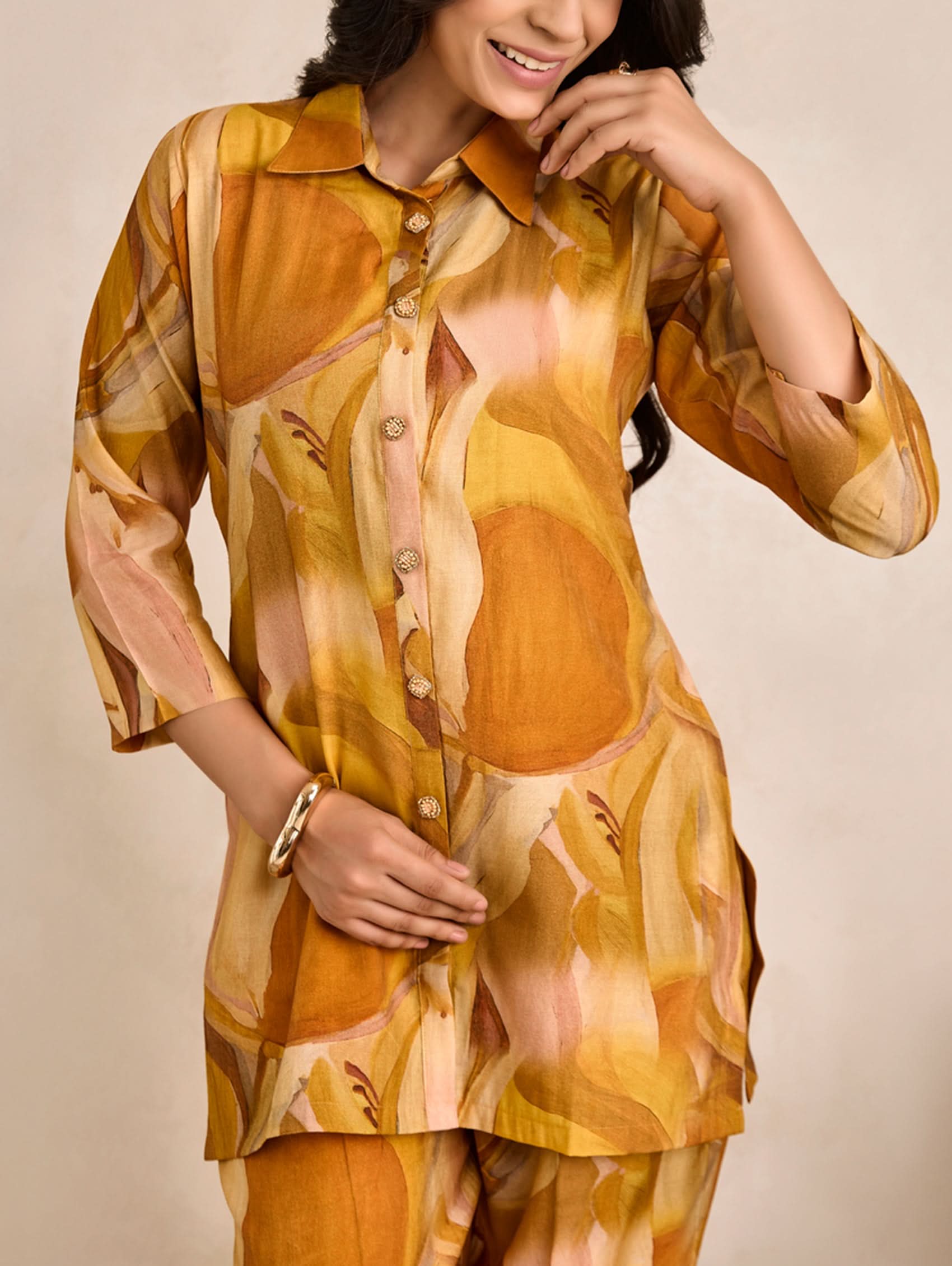 Woman wearing a patterned orange and yellow outfit against a beige background