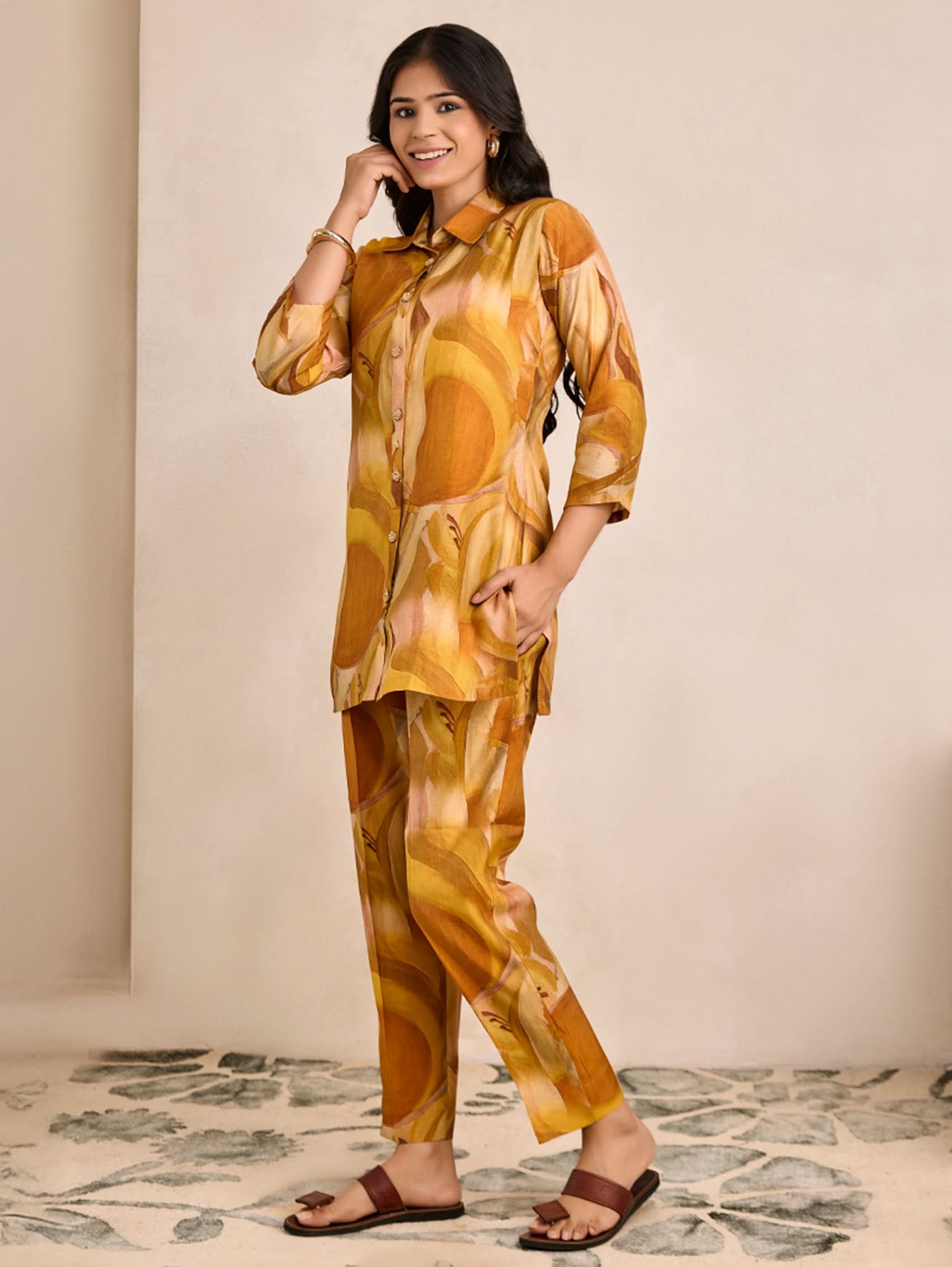 Woman wearing a mustard yellow patterned outfit against a neutral background