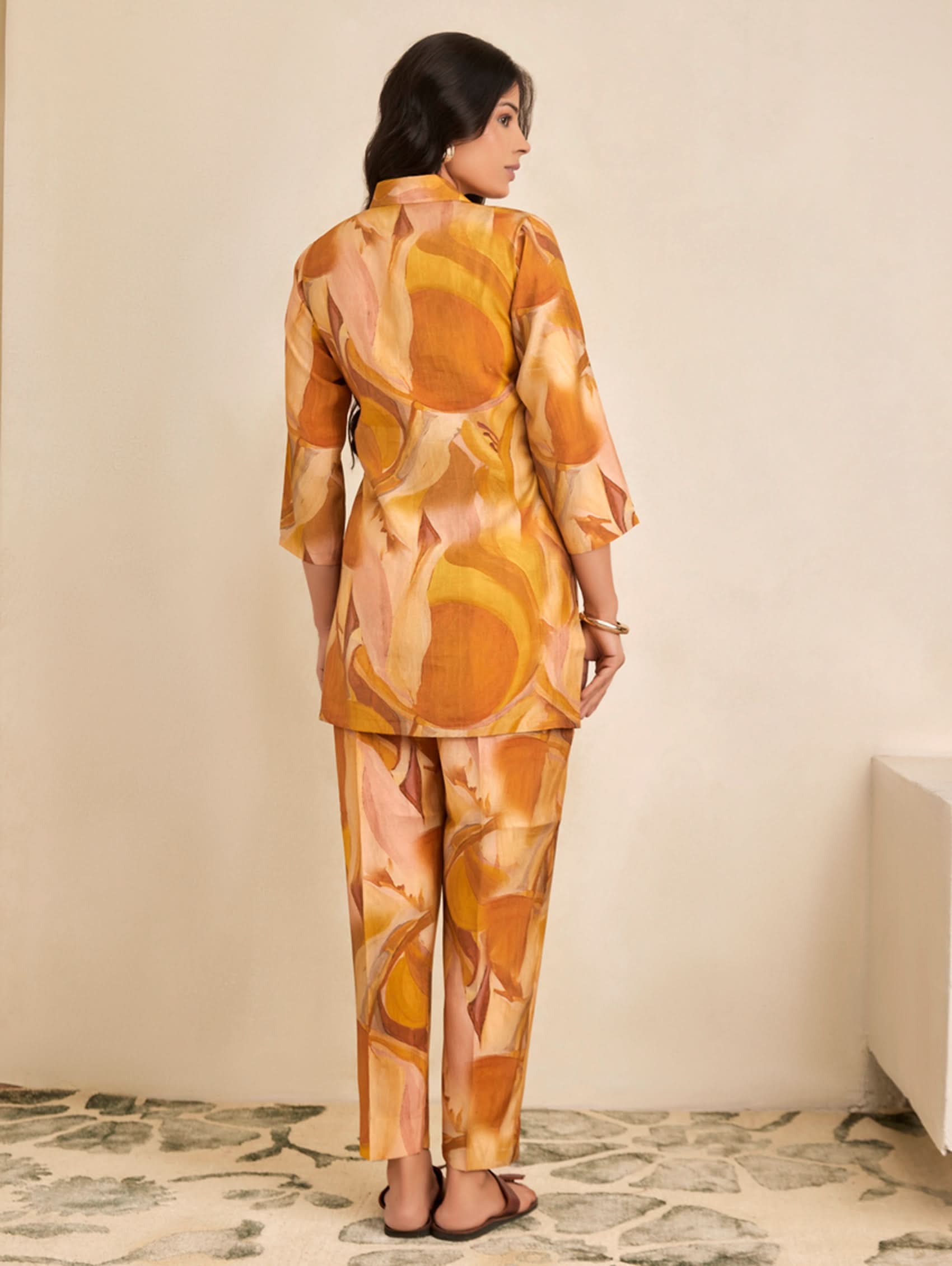 Woman wearing a patterned outfit standing against a plain background
