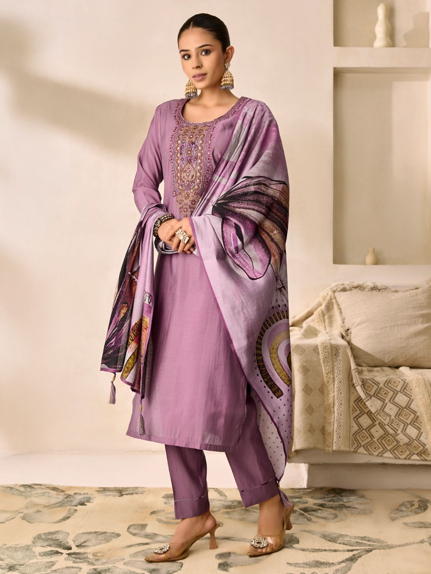Woman wearing a purple traditional outfit with a matching dupatta in a well-lit room.