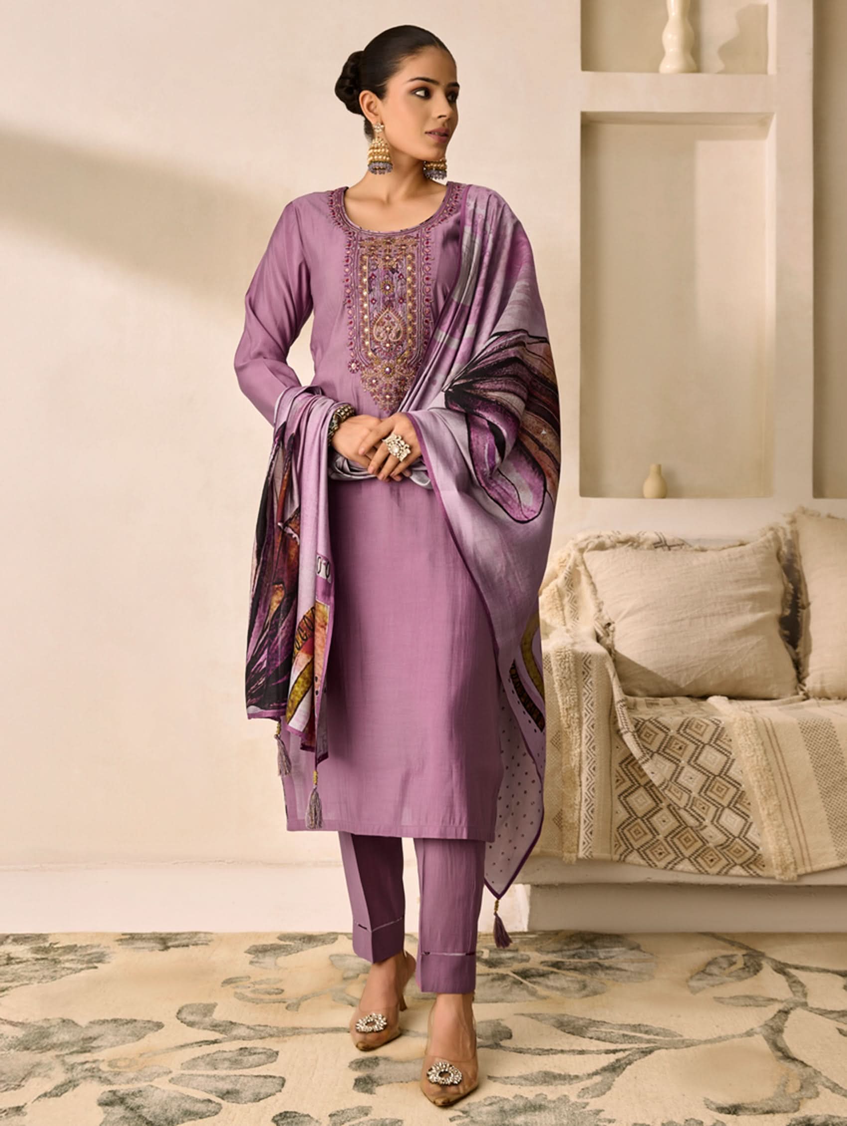 Woman in a purple traditional outfit with a matching dupatta in a living room setting.