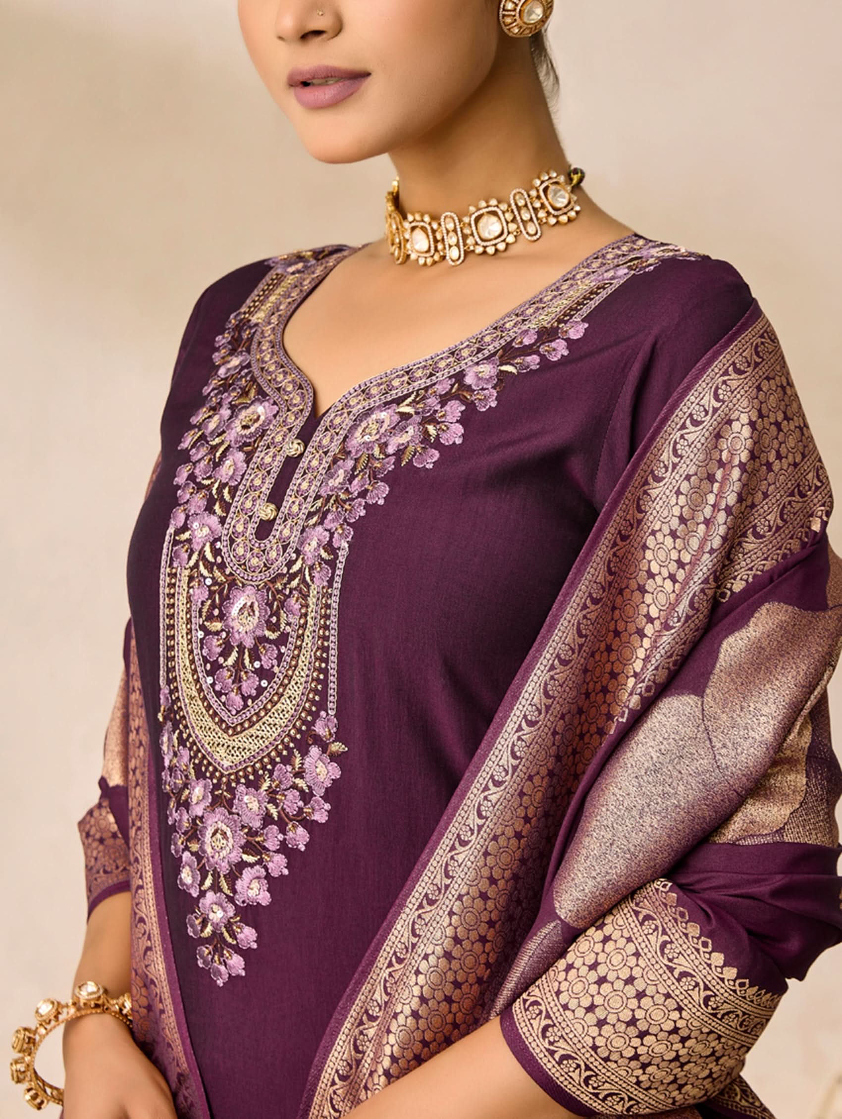 Purple embroidered garment with gold detailing on a neutral background