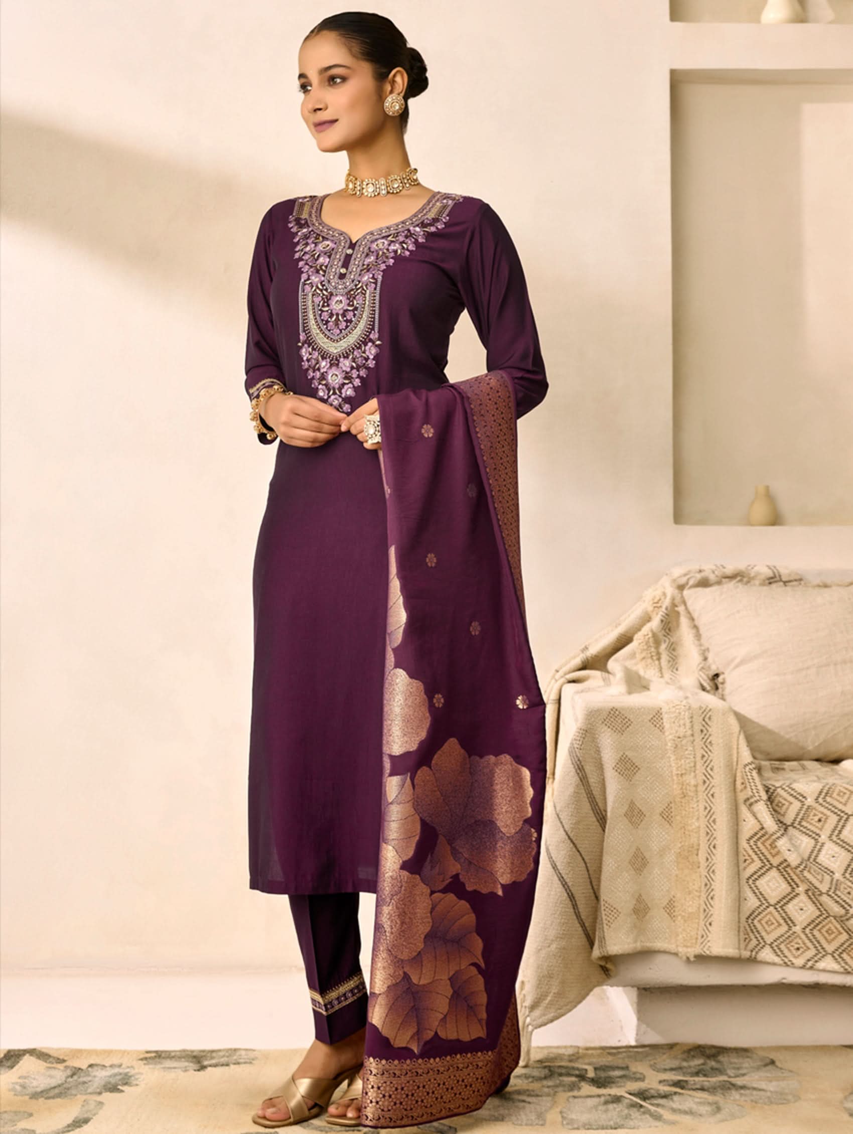 Woman wearing a purple embroidered outfit with a matching dupatta in a neutral setting