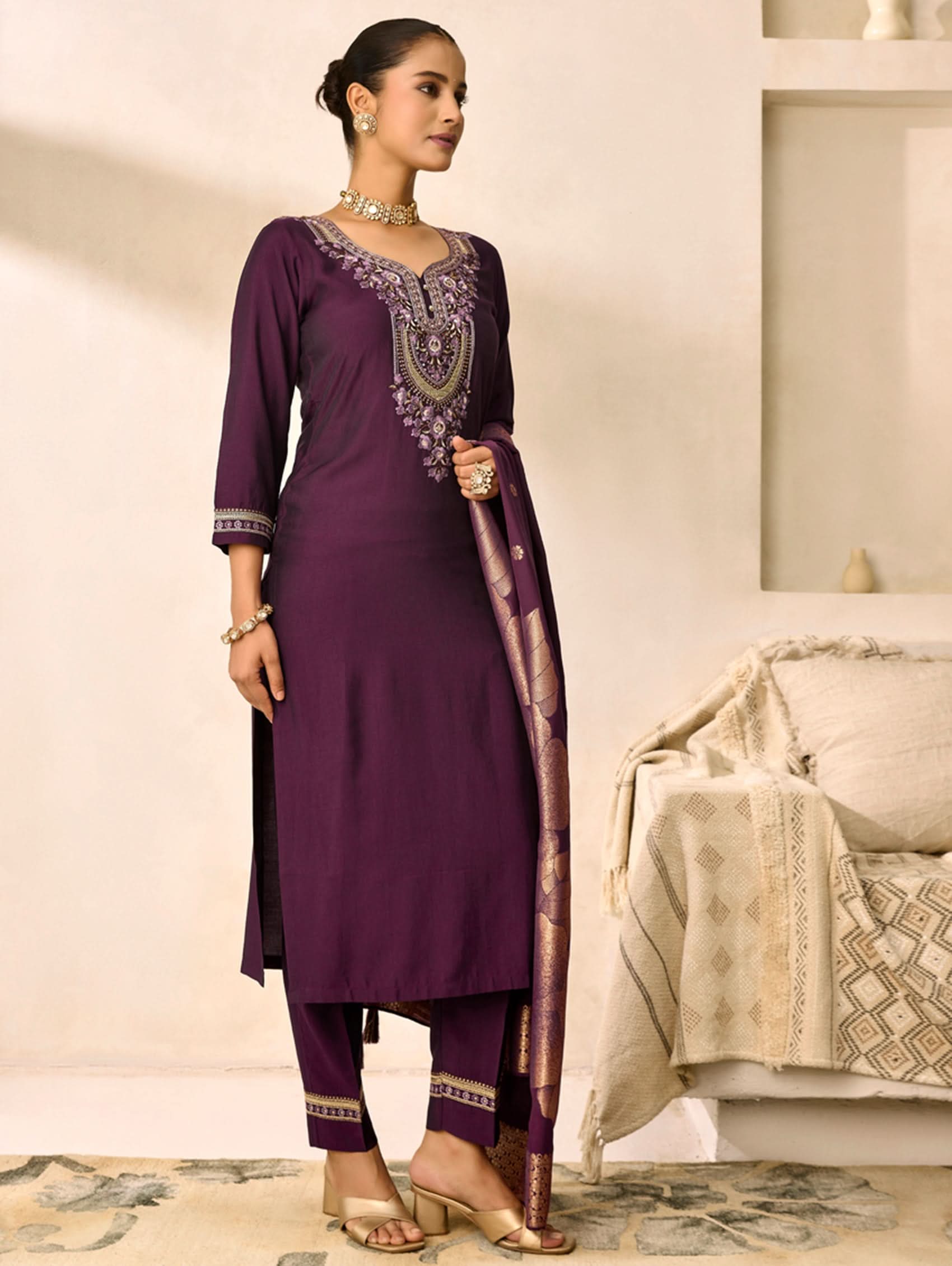 Woman wearing a purple traditional outfit with embroidery in a room.