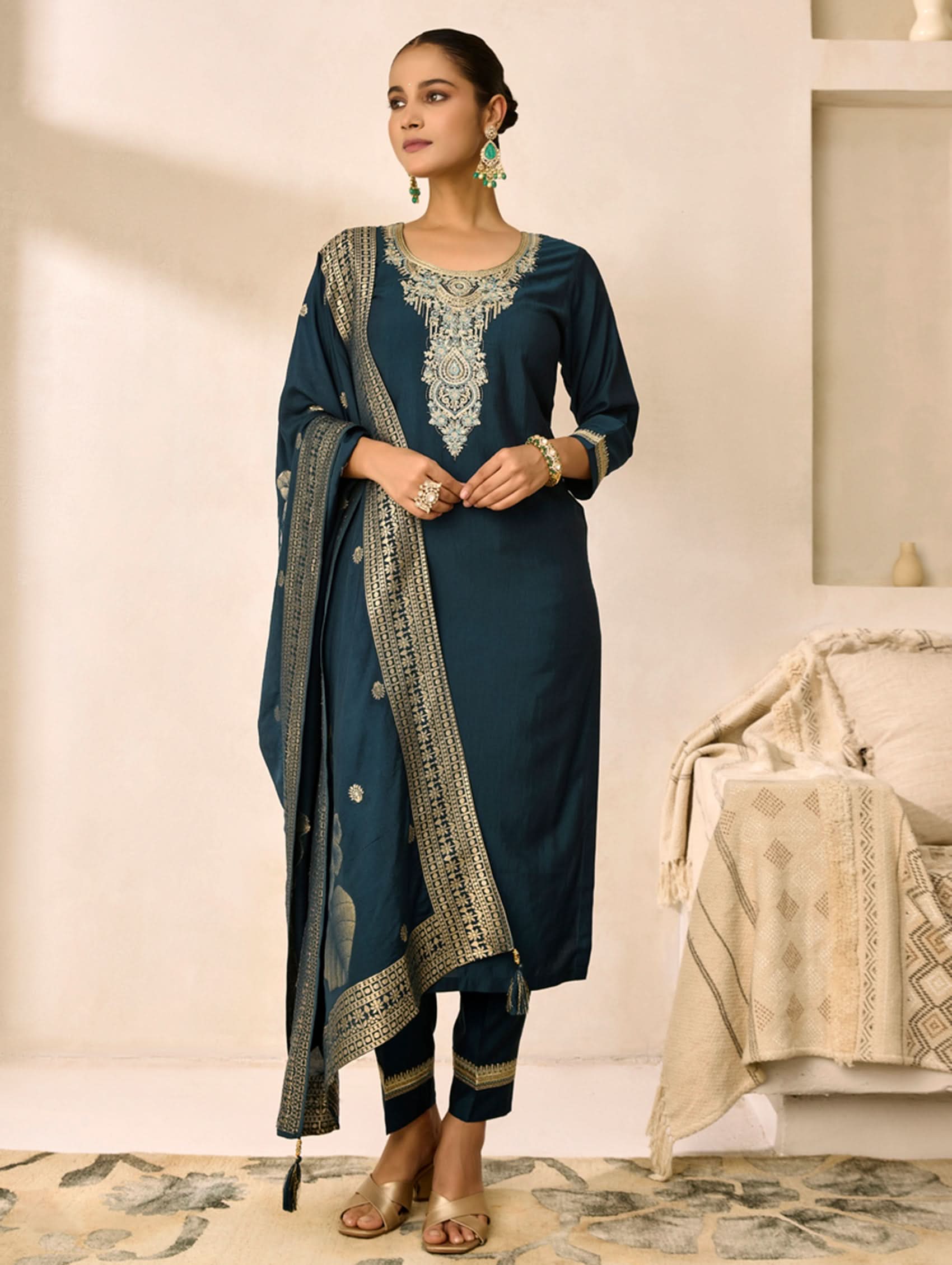 Woman wearing a dark blue embroidered traditional outfit in a well-lit room.