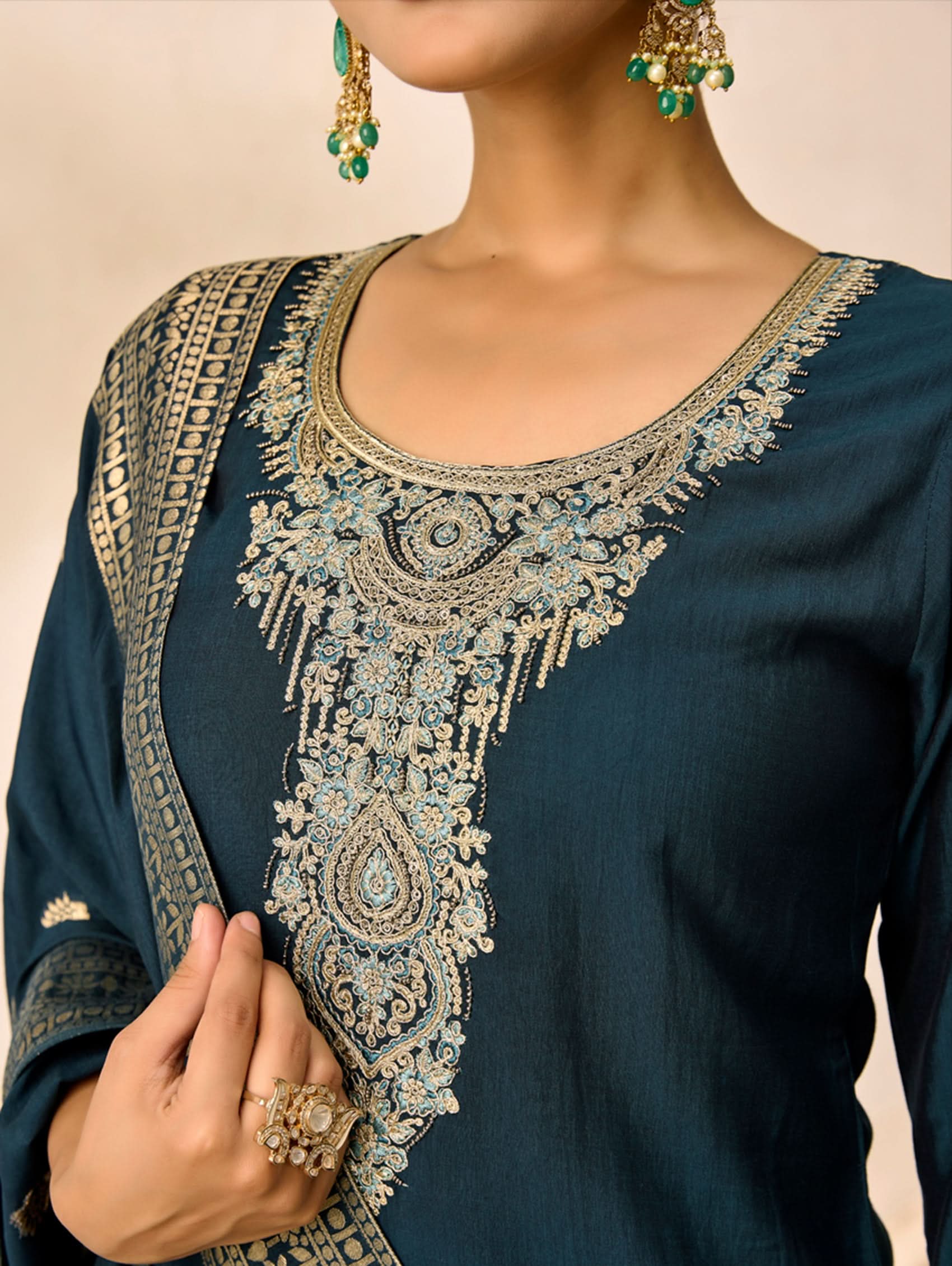 Blue embroidered traditional outfit with gold detailing on a beige background