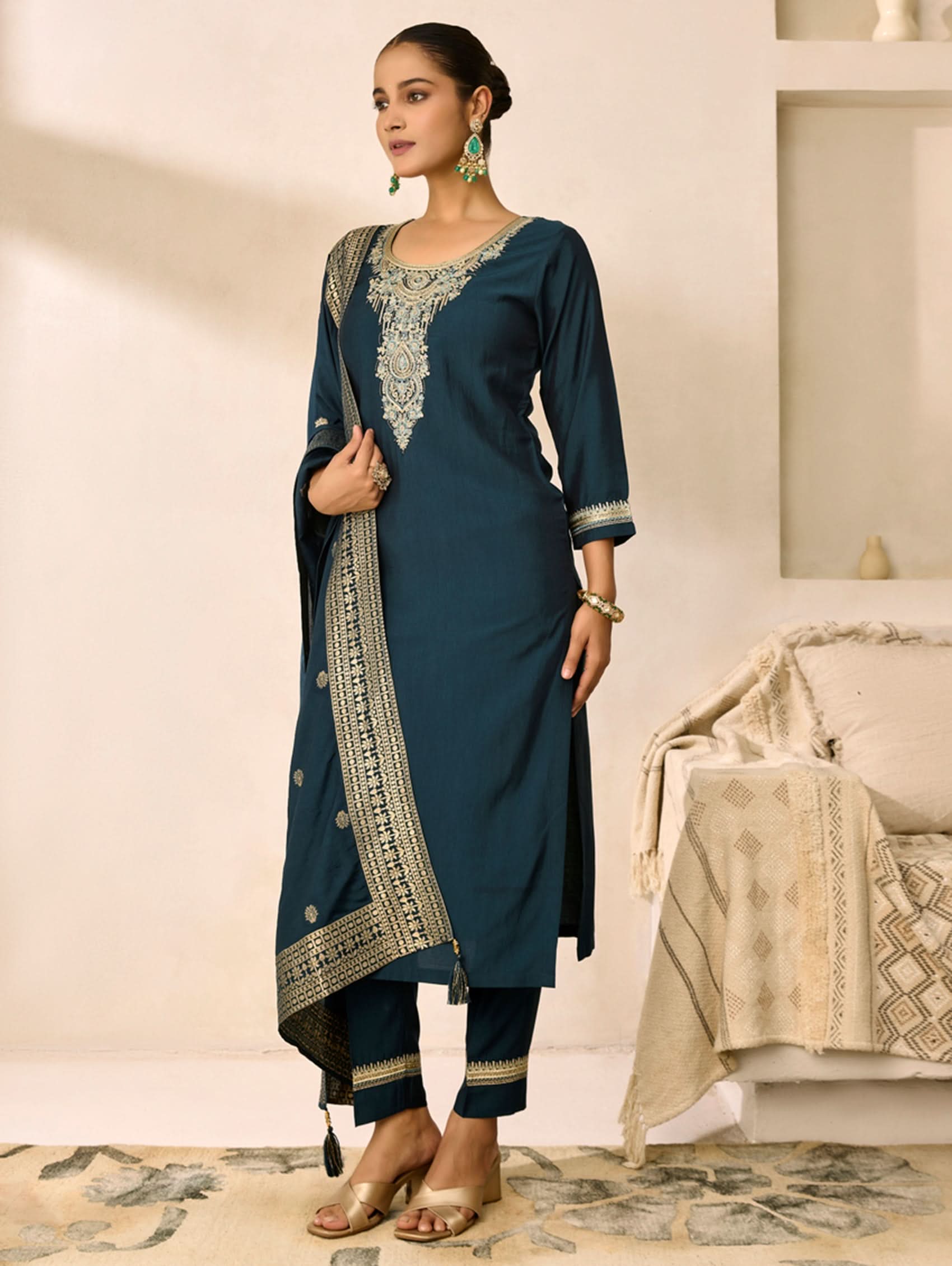 Woman wearing a blue traditional outfit with intricate embroidery in a well-lit room.