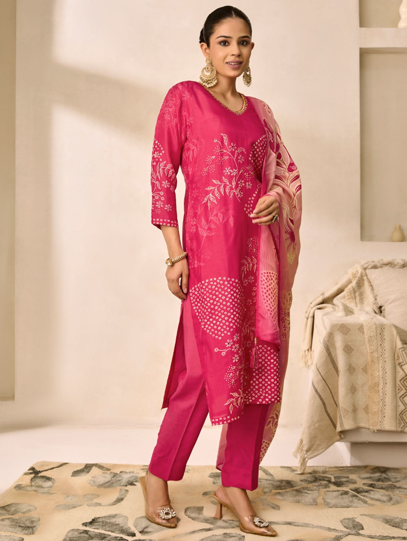 Woman wearing a pink traditional outfit with white patterns in a neutral setting