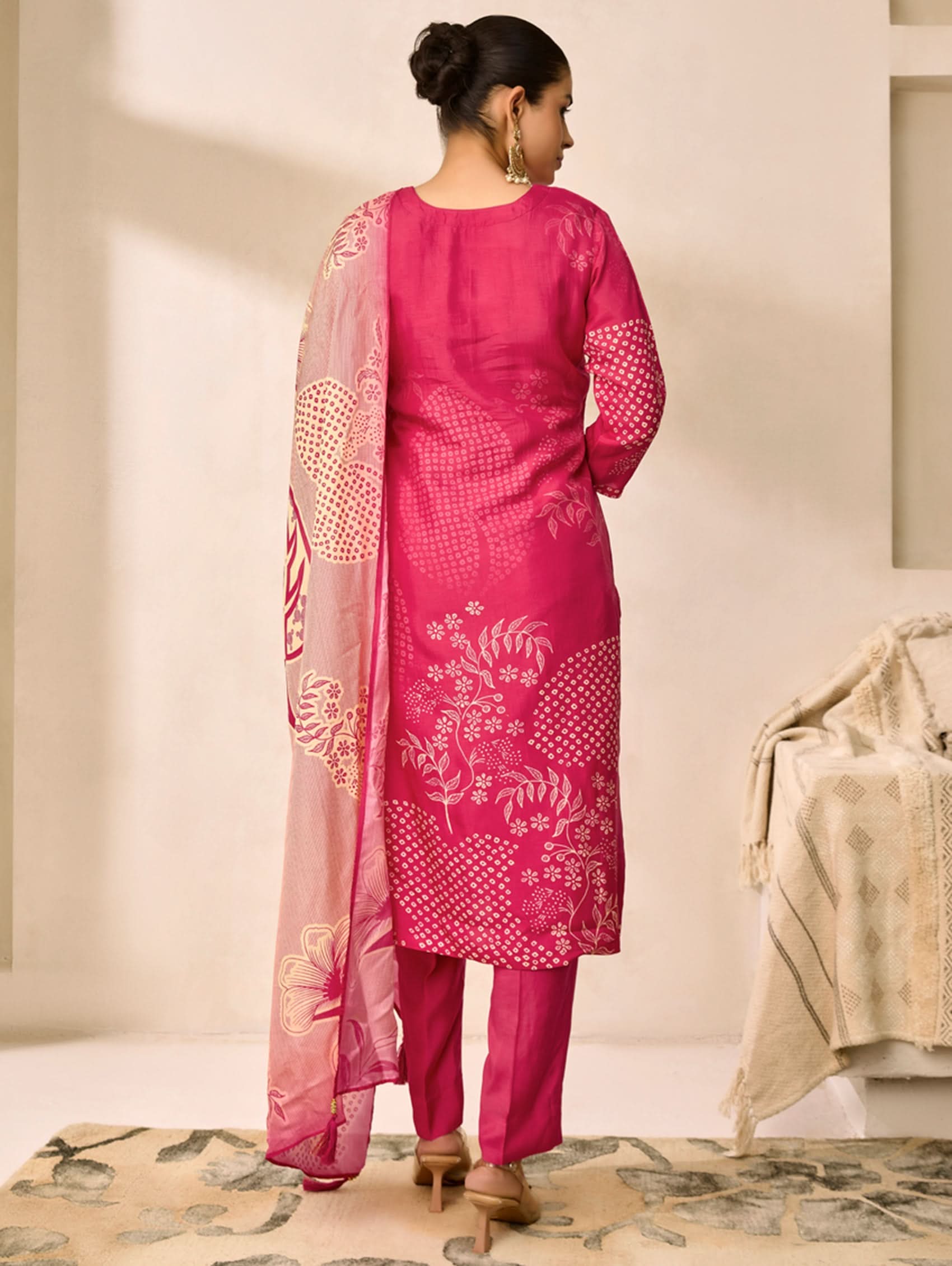 Woman wearing a pink traditional outfit with a matching dupatta in a minimalistic setting.