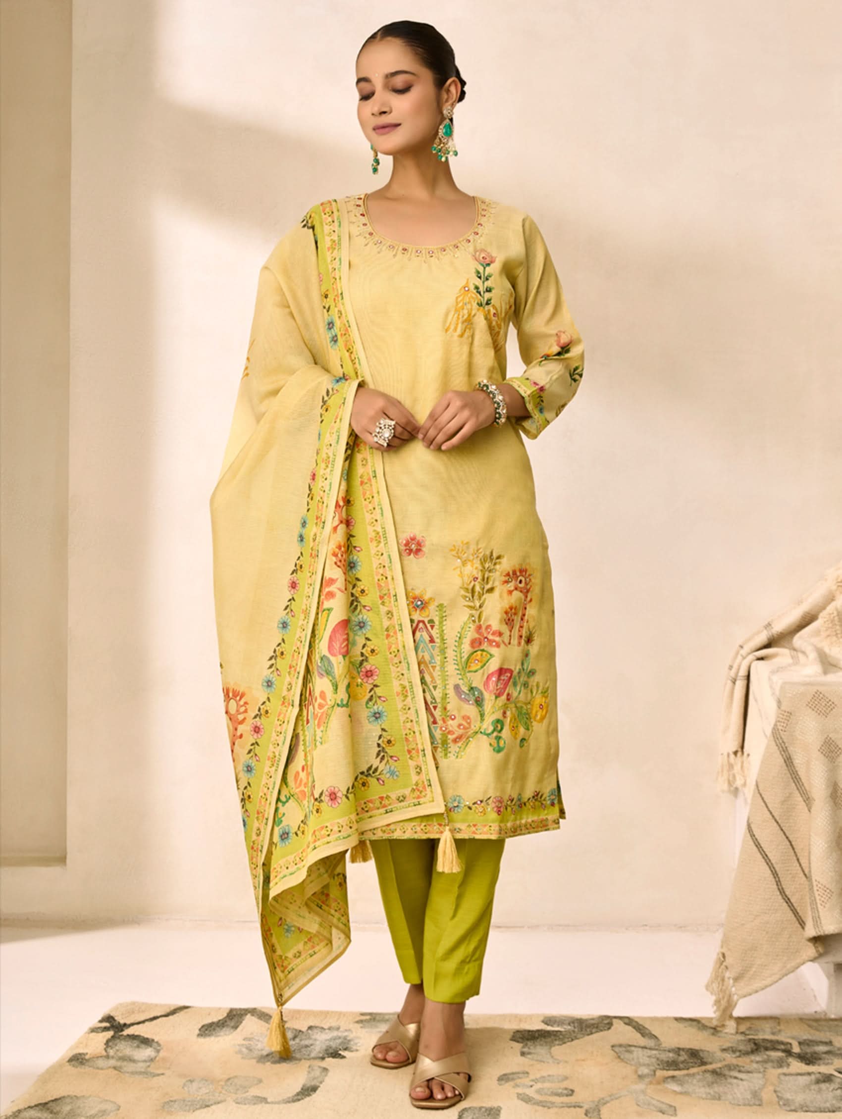 Woman wearing a light yellow traditional outfit with floral patterns in a neutral setting