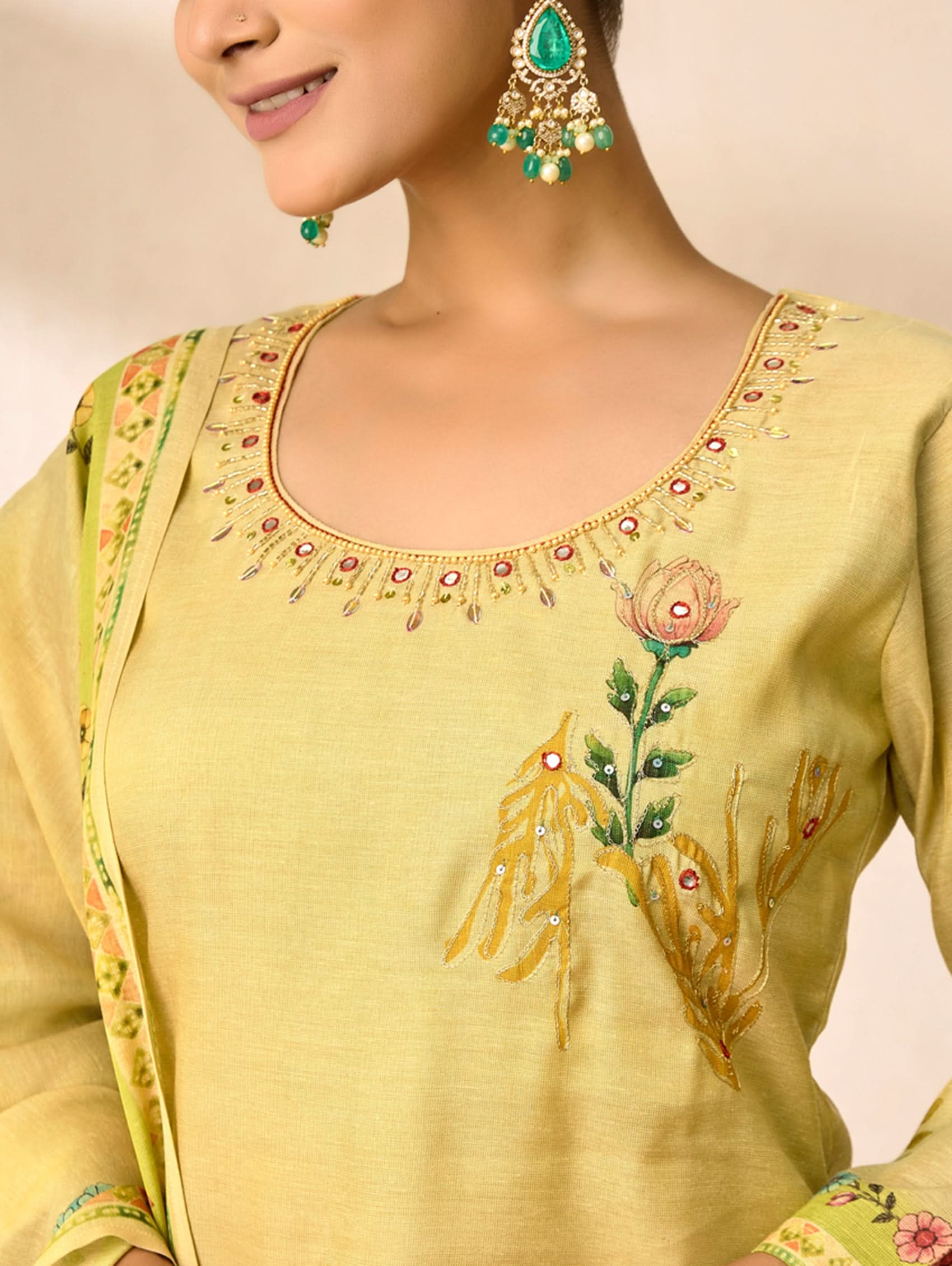 Light green embroidered traditional outfit with floral patterns on a neutral background