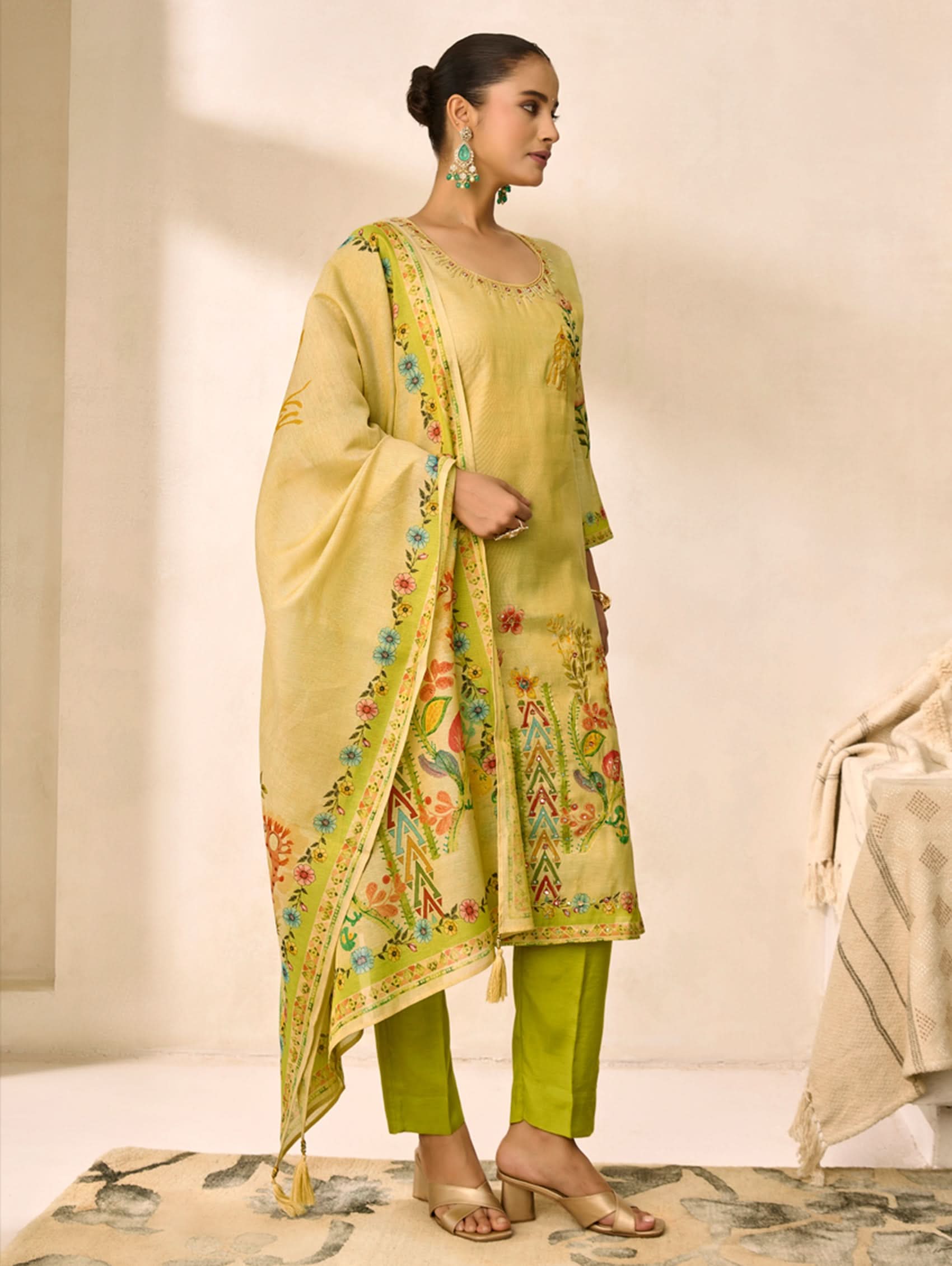Woman wearing a light green traditional outfit with floral patterns on a neutral background