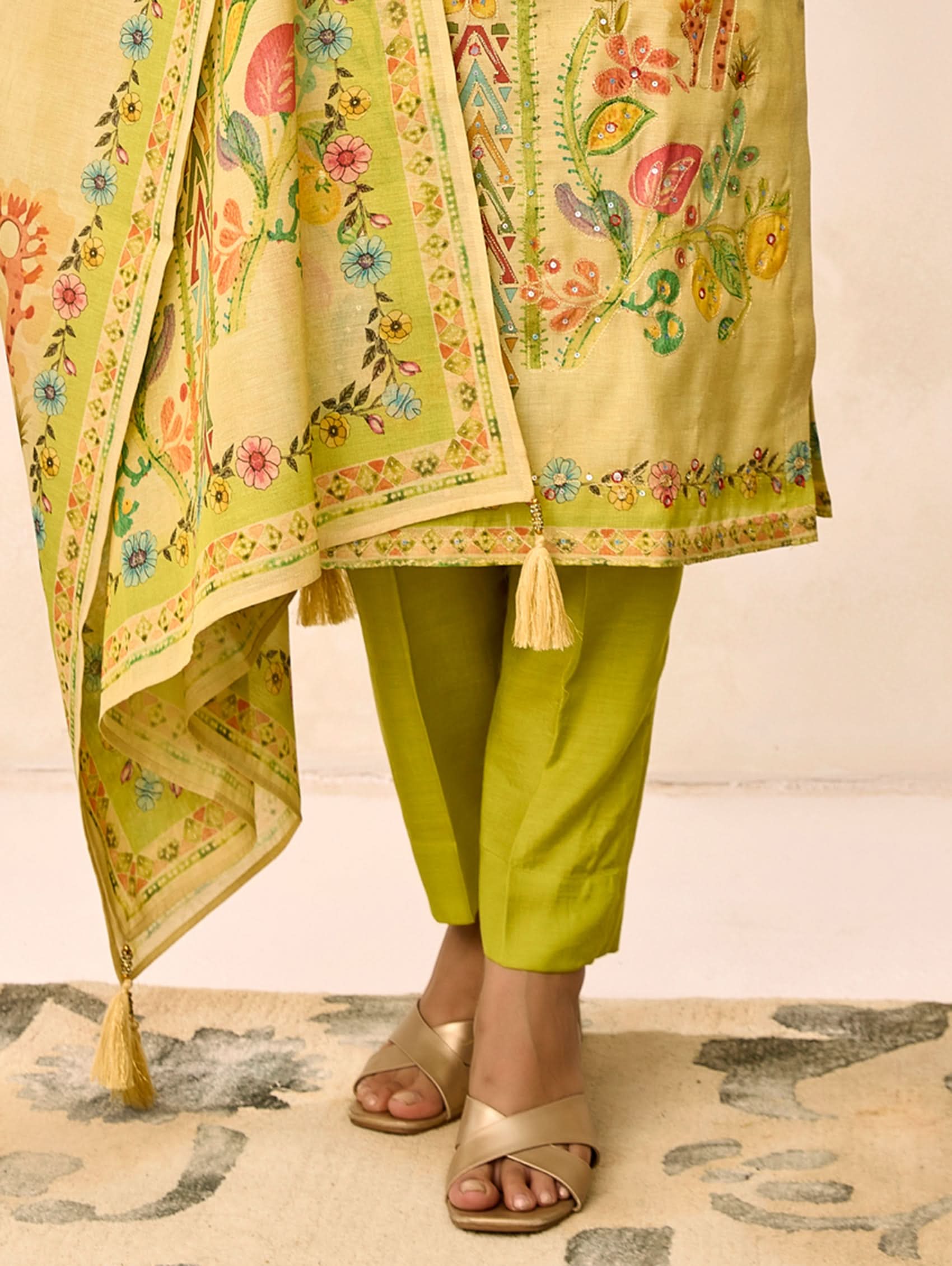 Traditional outfit with a floral dupatta and green pants on a neutral background