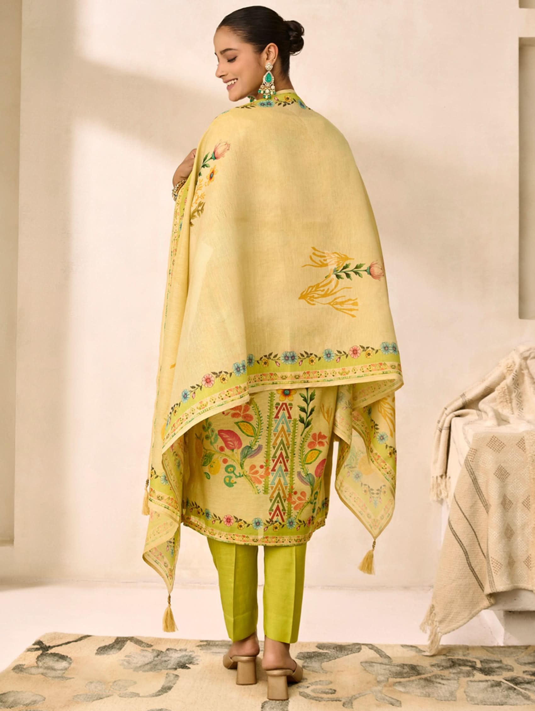 Woman wearing a light yellow embroidered dupatta with green pants in a minimalistic setting