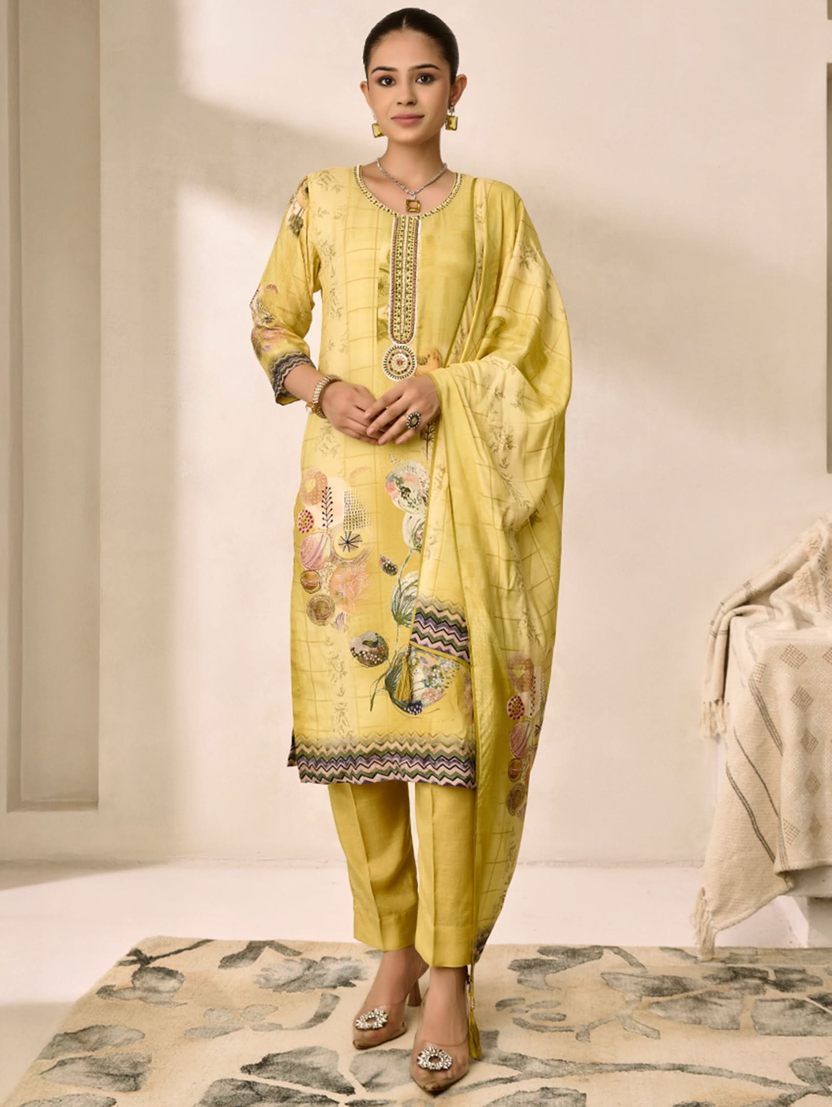 Woman wearing a yellow embroidered traditional outfit with a matching dupatta on a neutral background