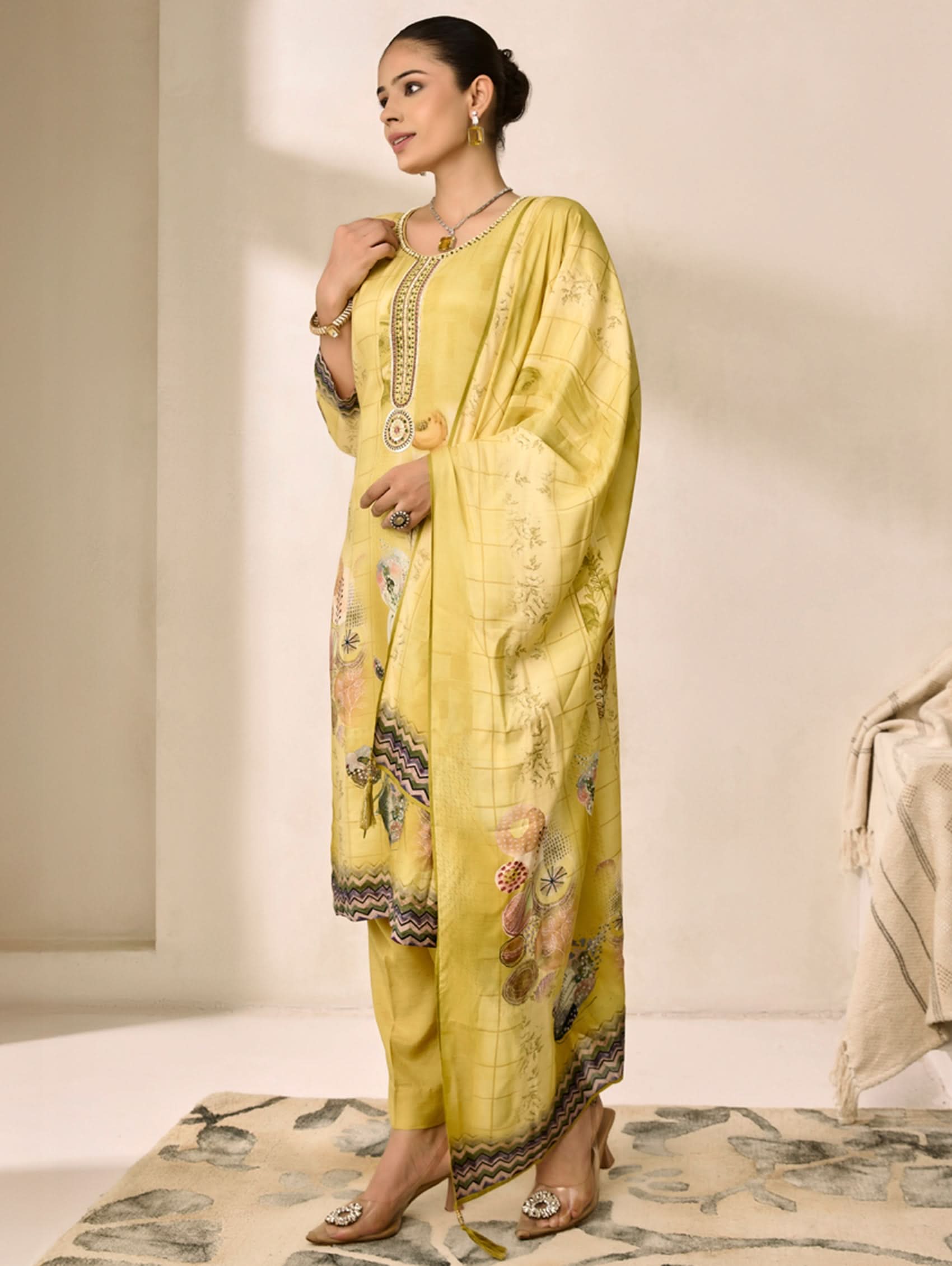 Woman wearing a yellow traditional outfit with intricate patterns on a neutral background