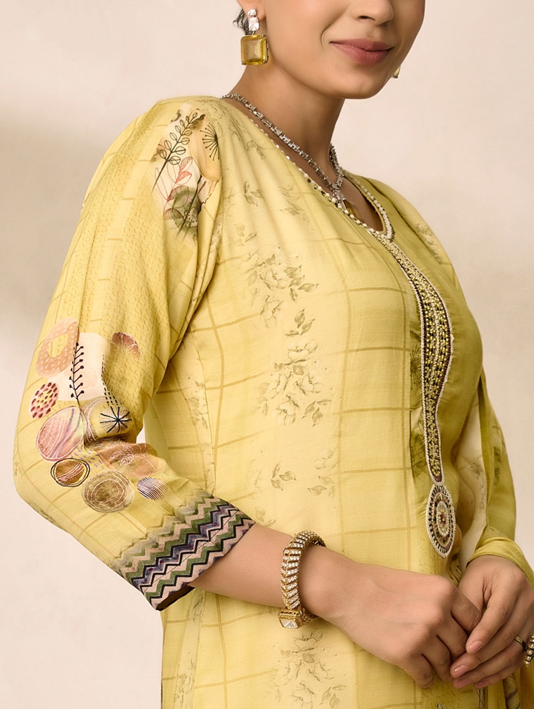 Woman wearing a yellow embroidered traditional outfit with a neutral background
