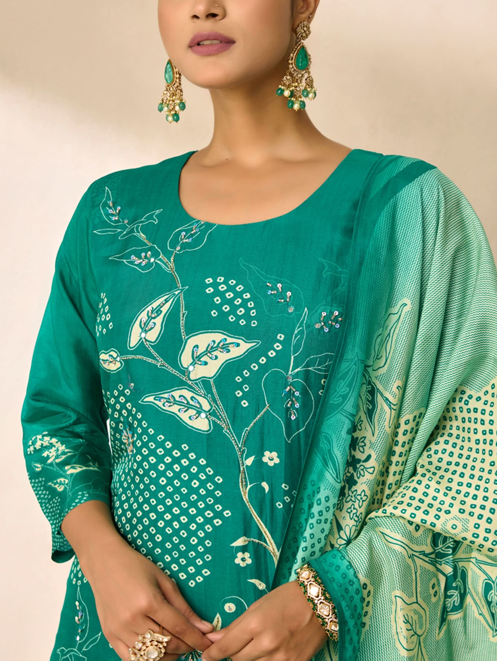 Woman wearing a green embroidered traditional outfit with a beige background