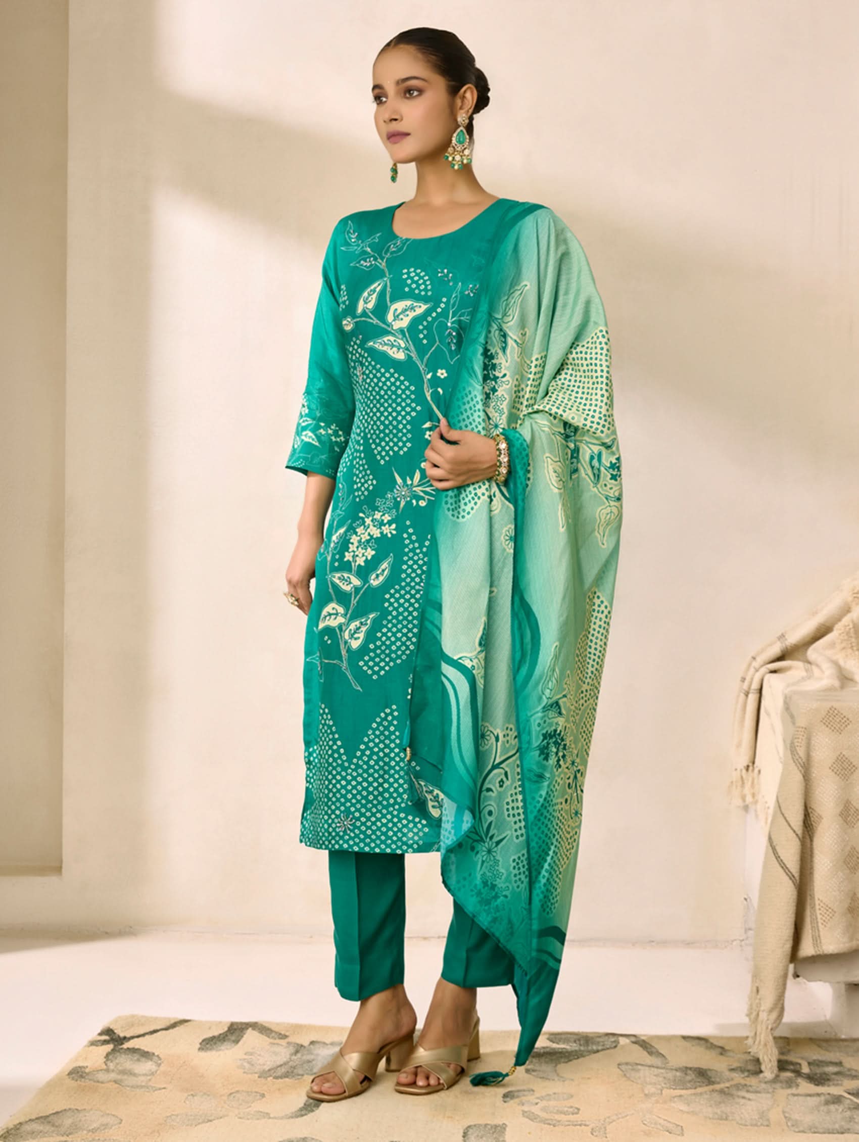 Woman wearing a teal traditional outfit with a matching dupatta against a neutral background