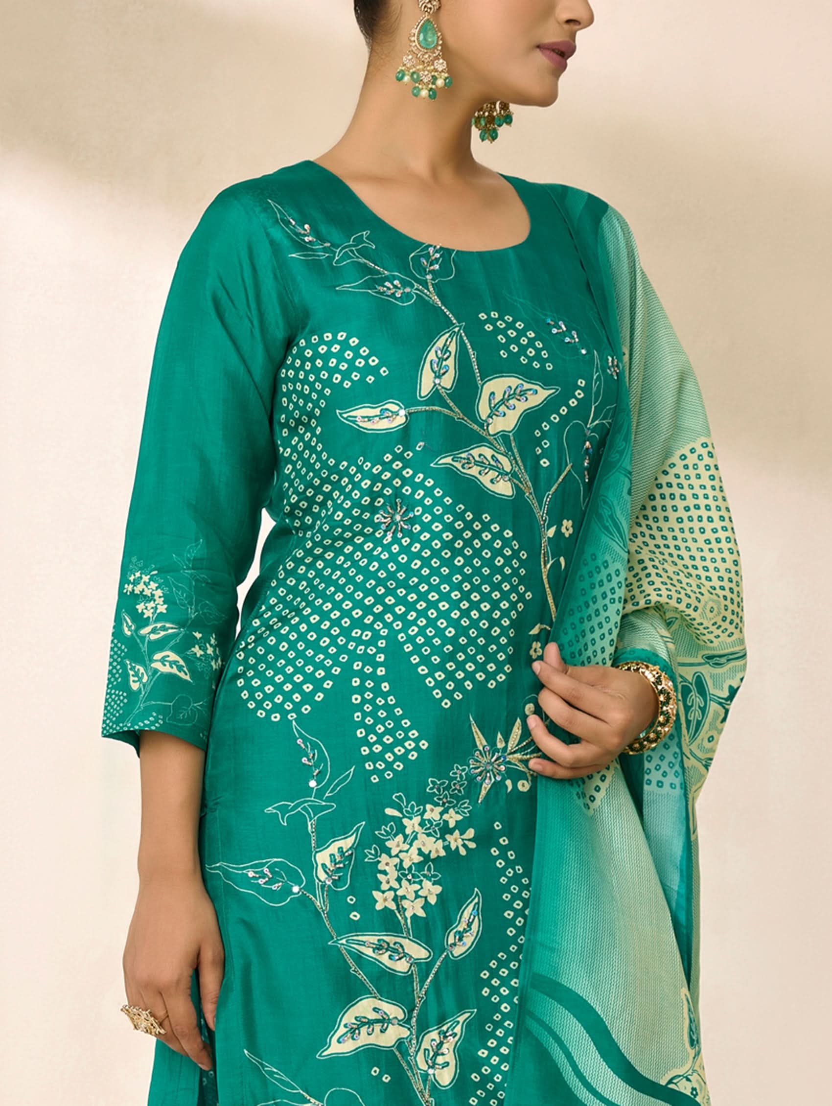 Teal traditional outfit with floral patterns on a plain background