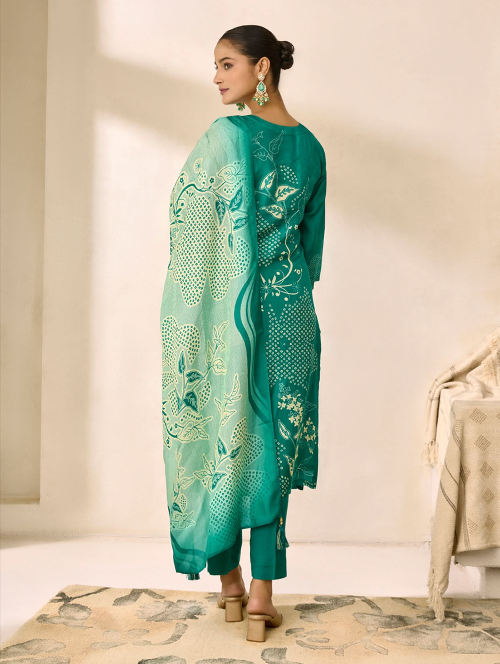 Woman wearing a green embroidered outfit in a minimalistic setting