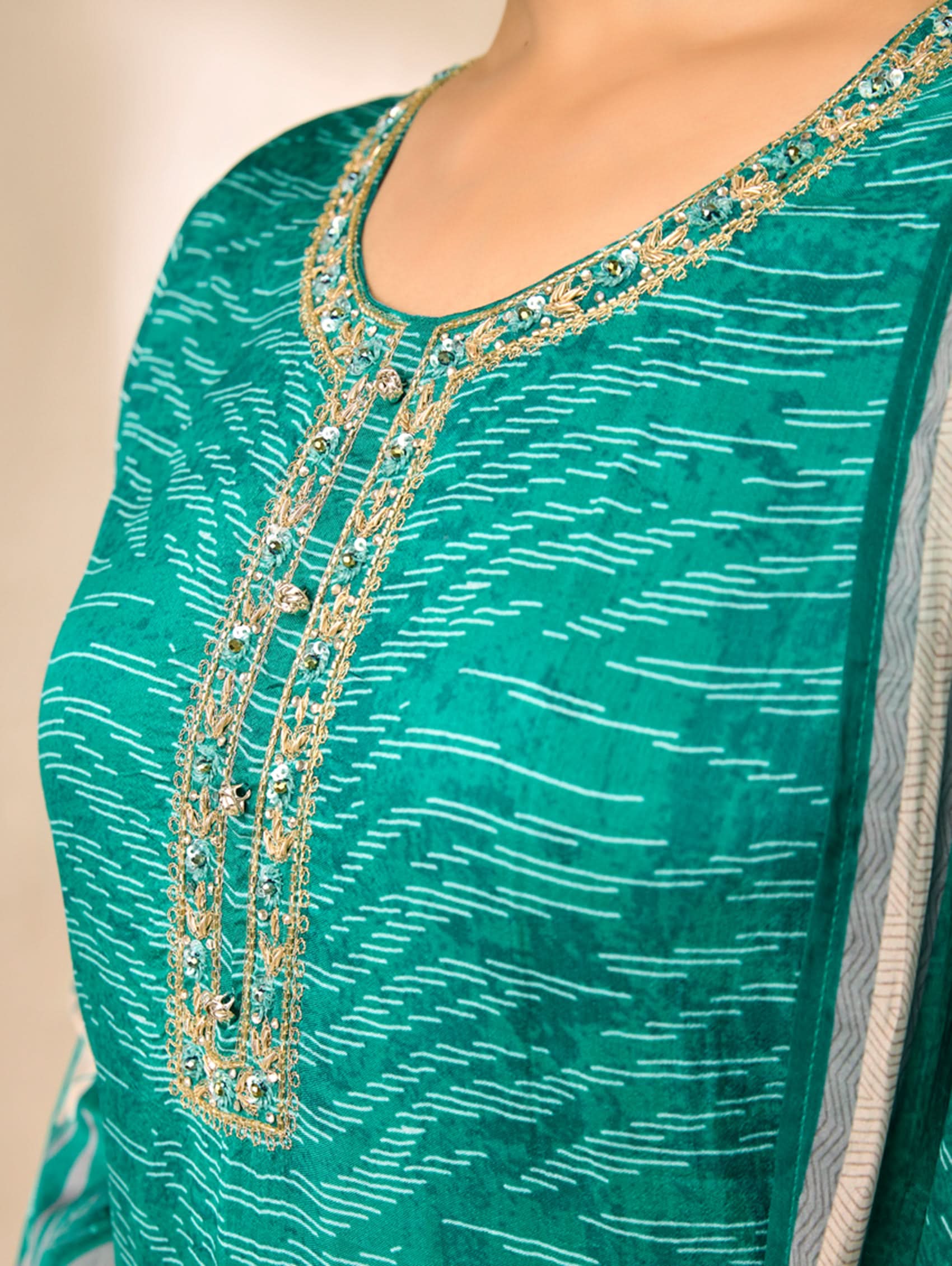 Green traditional outfit with gold embroidery on a beige background