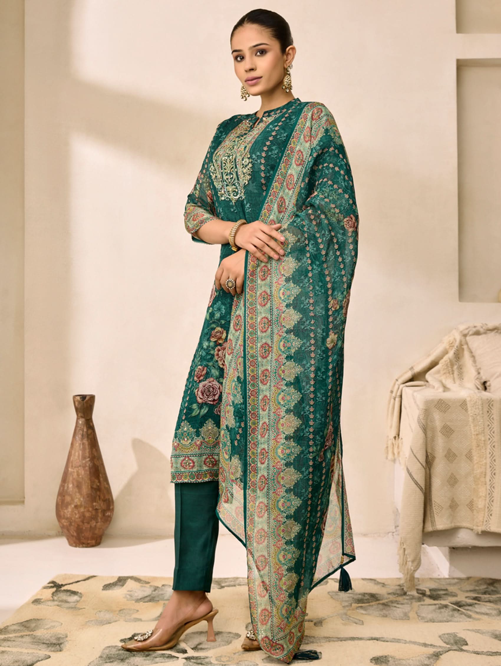 Woman wearing a teal embroidered outfit in an indoor setting