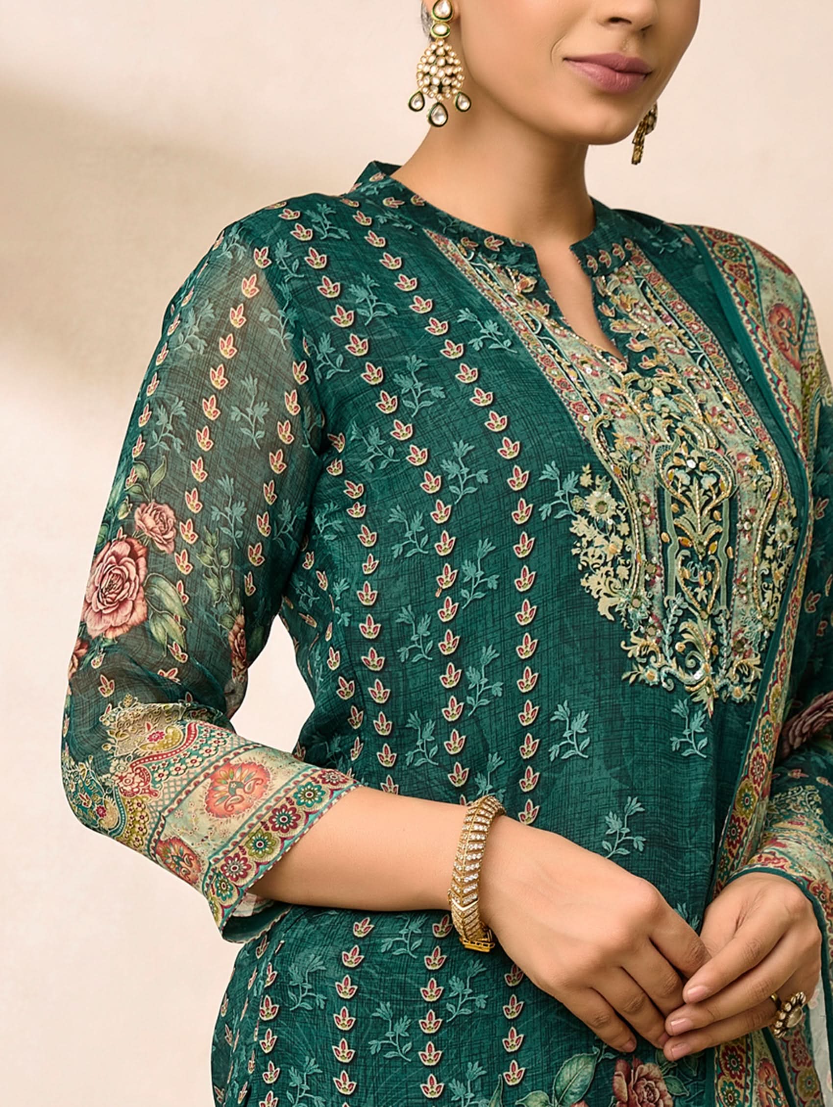Woman wearing a green embroidered traditional outfit with floral patterns.