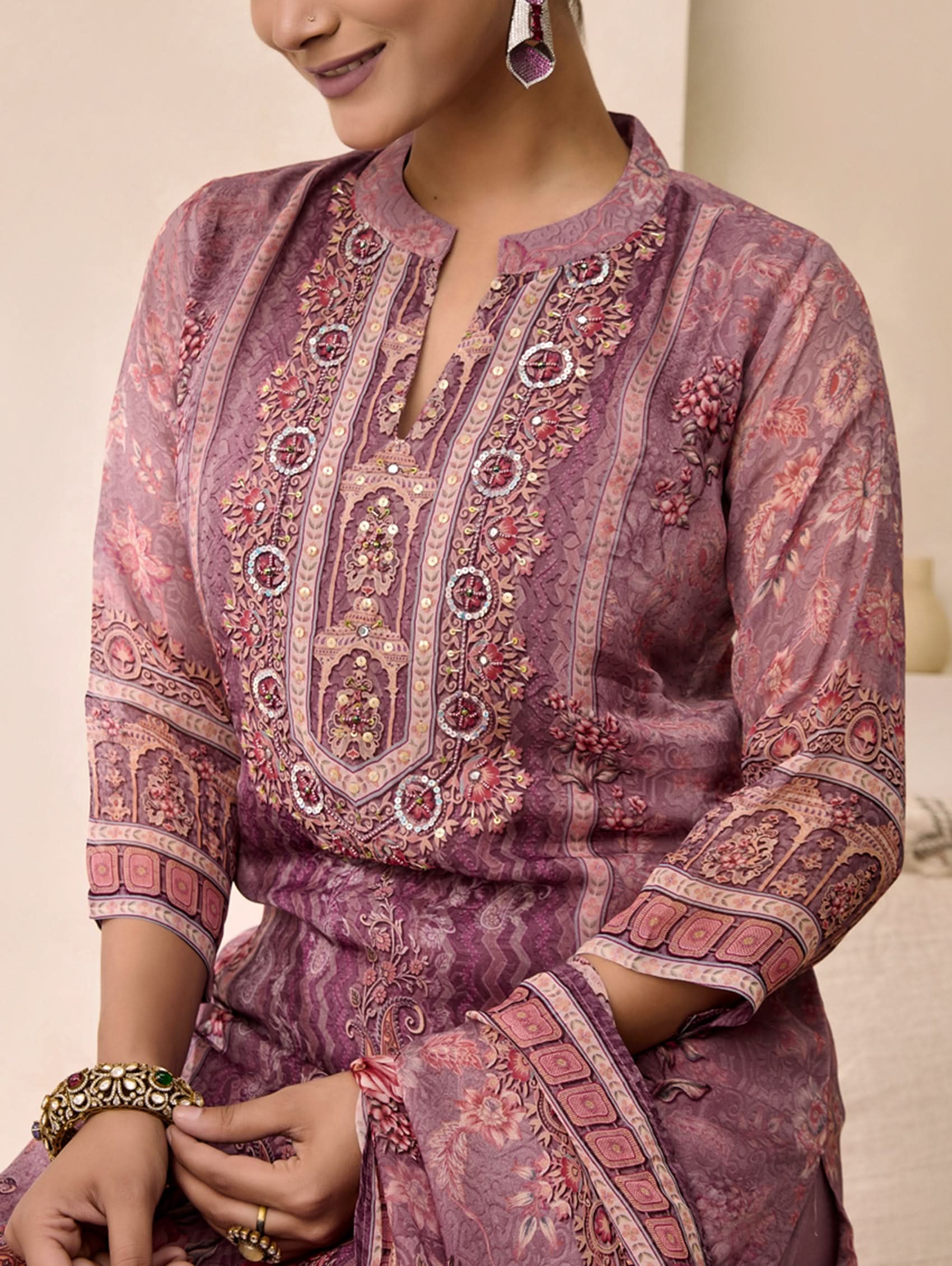 Woman wearing a intricately patterned purple outfit with detailed embroidery.