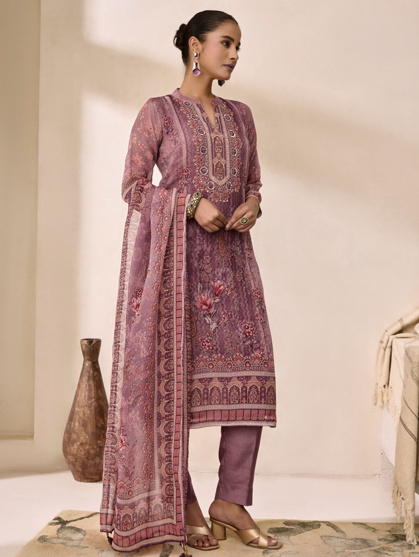 Woman wearing a traditional outfit with intricate patterns in a minimalistic setting