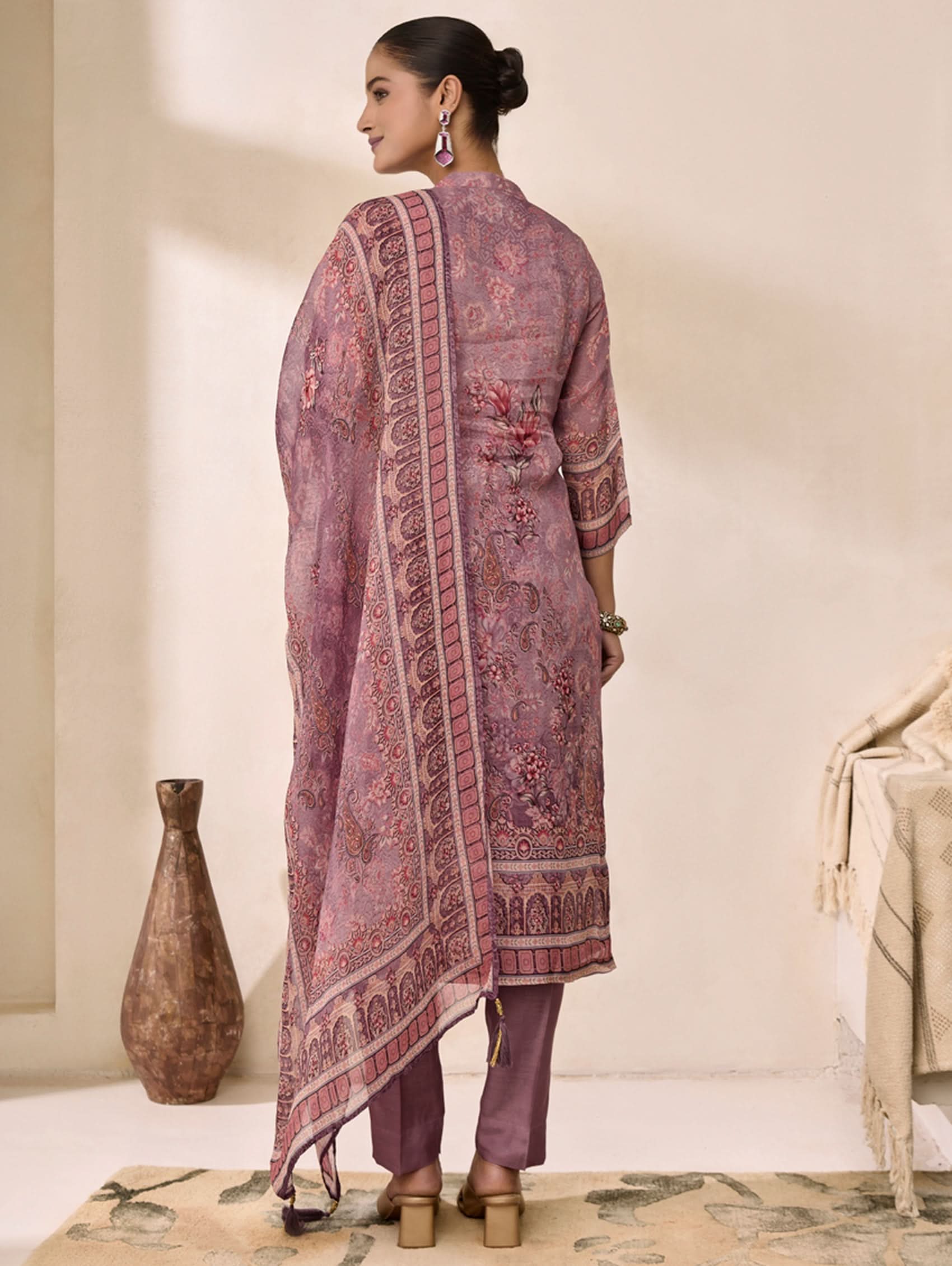 Woman wearing a traditional pink embroidered outfit in a minimalistic setting