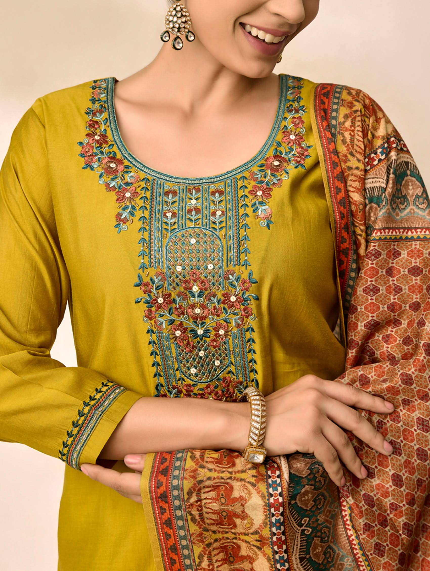 Woman wearing a mustard yellow kurta with intricate embroidery, holding a matching dupatta.