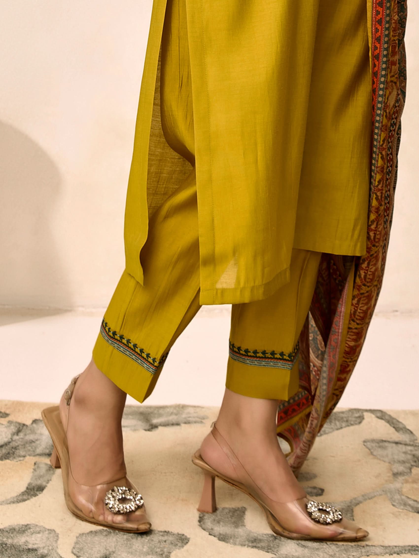 Yellow traditional outfit with patterned fabric and high-heeled sandals on a neutral background