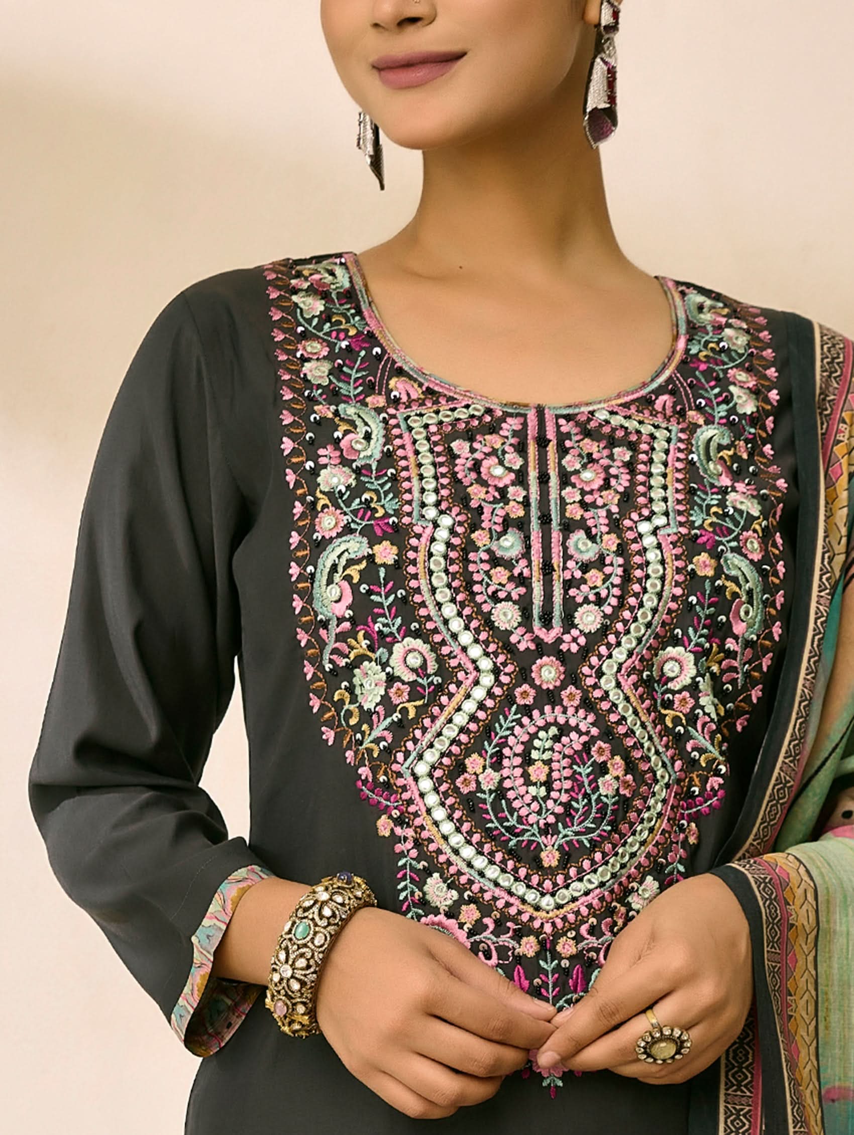 Woman wearing a black kurta with intricate embroidery on a beige background