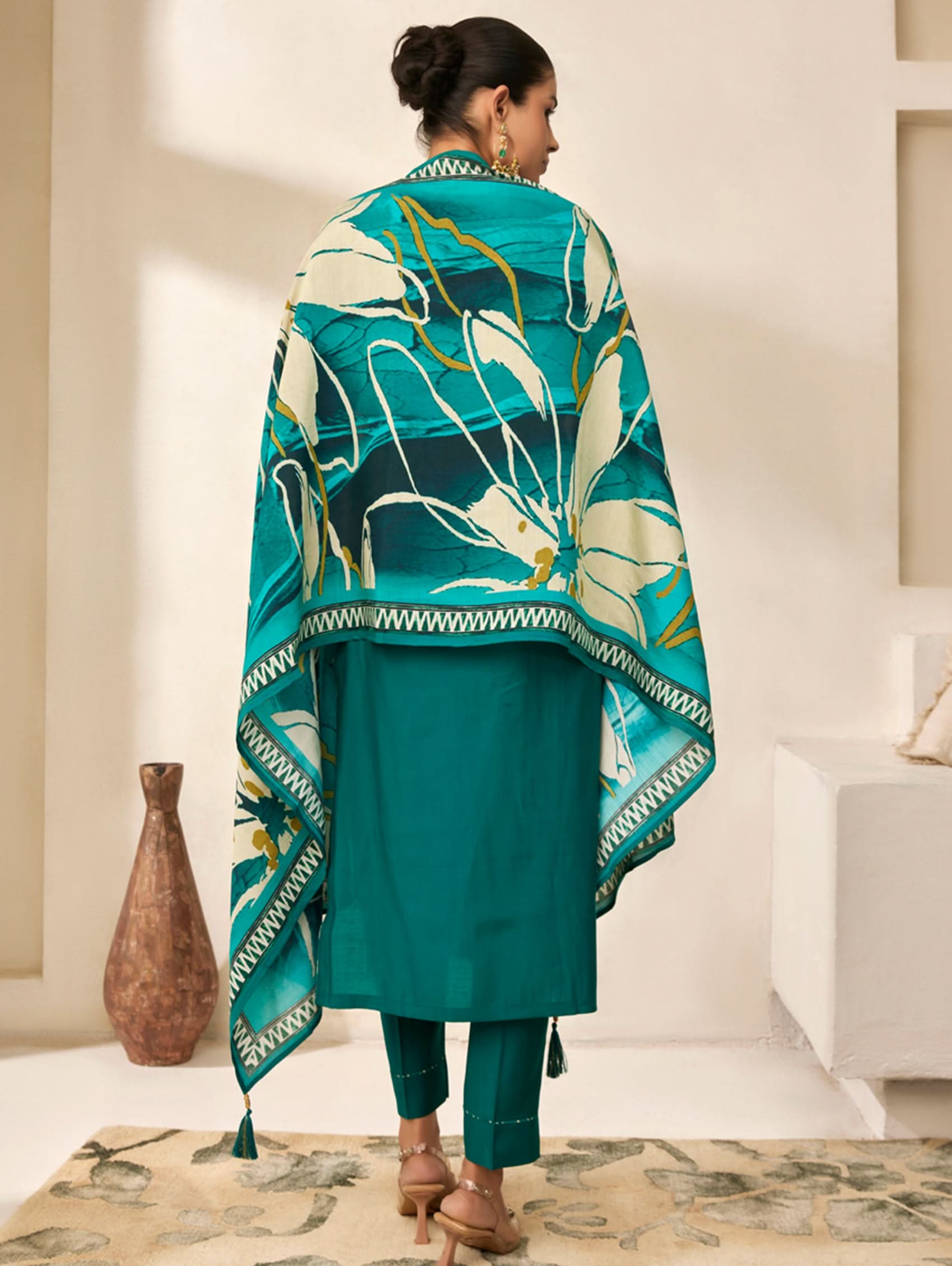 Woman wearing a teal outfit with a matching shawl in a room setting