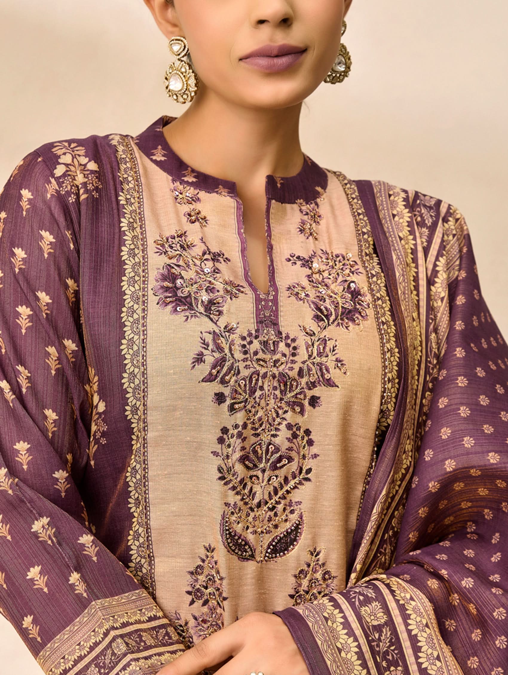 Close-up of a person wearing a purple and beige embroidered traditional outfit.