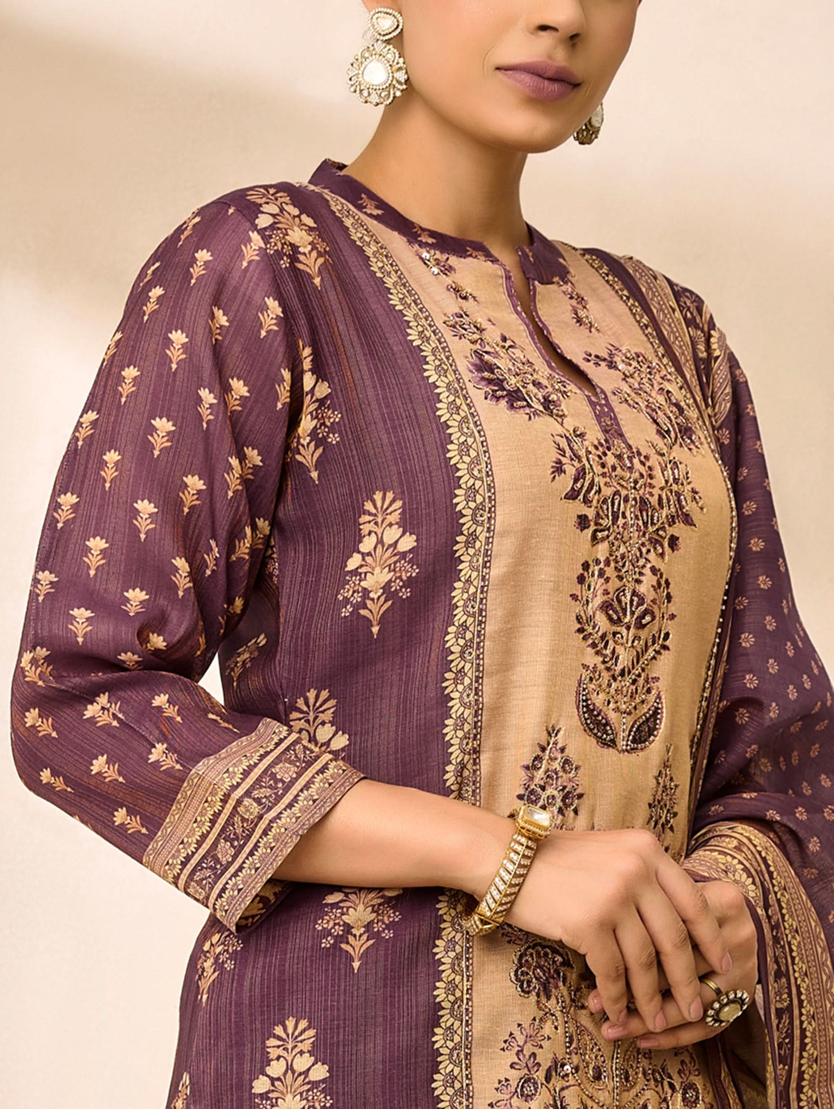 Woman wearing a traditional outfit with intricate patterns on a beige background