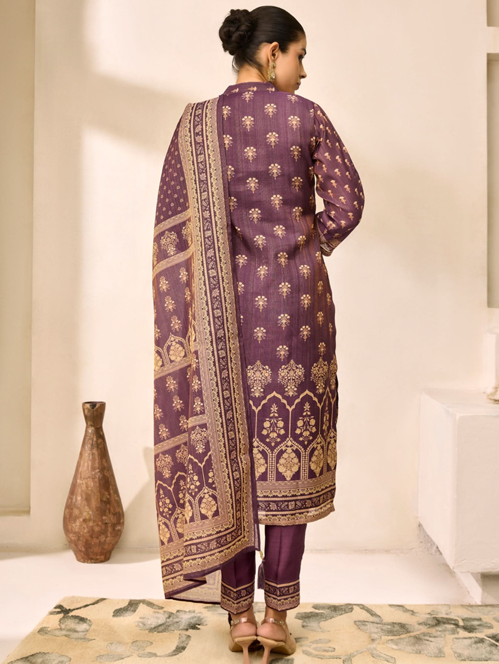 Woman wearing a purple embroidered traditional outfit with a white background