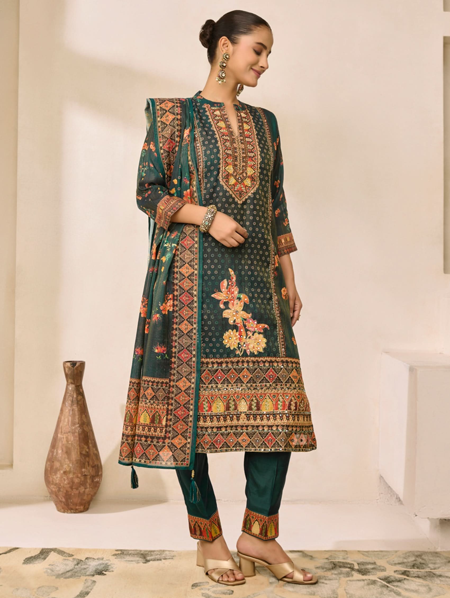 Woman wearing a traditional embroidered kurta with a vase and carpet in the background
