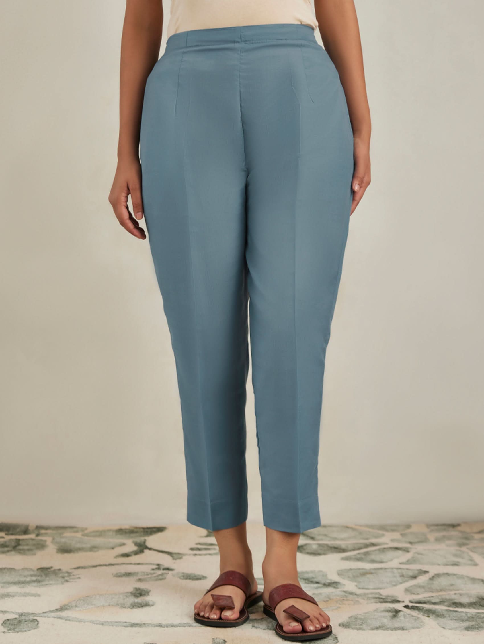 Person wearing blue pants standing on a patterned rug with a neutral background