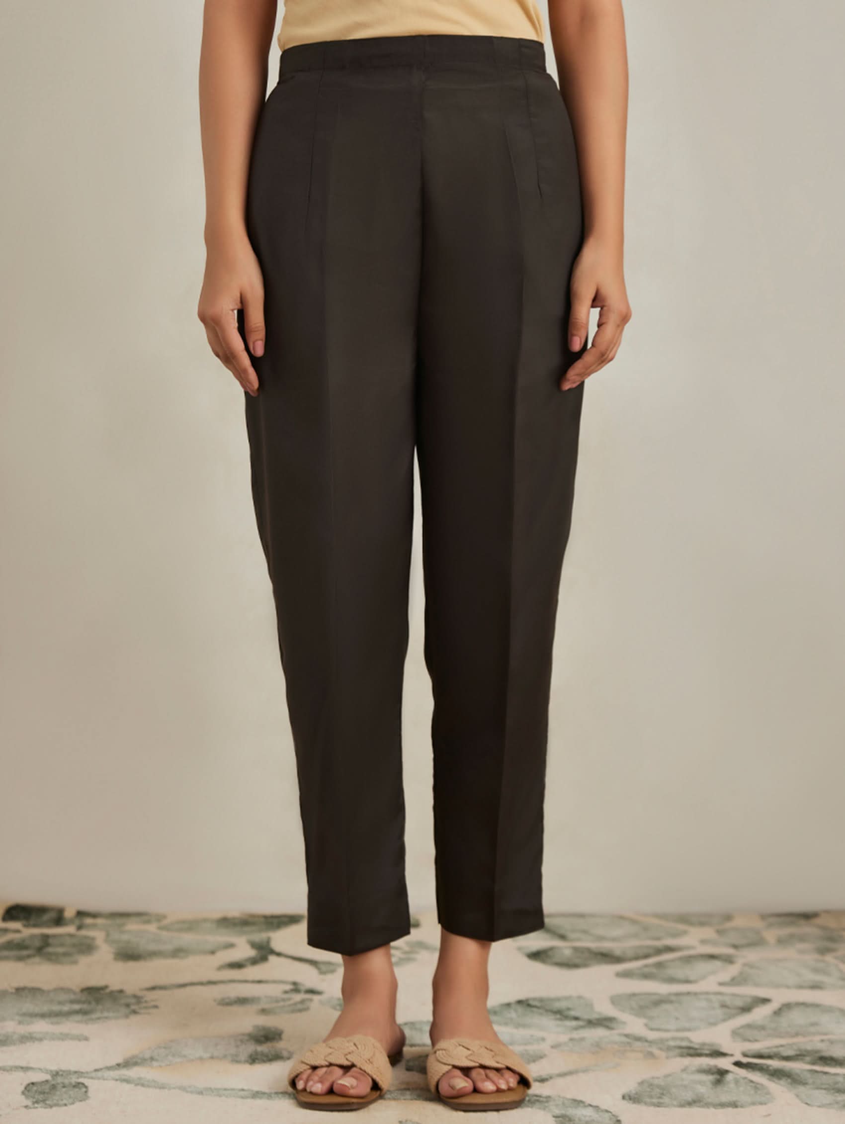 Person wearing black pants on a neutral background