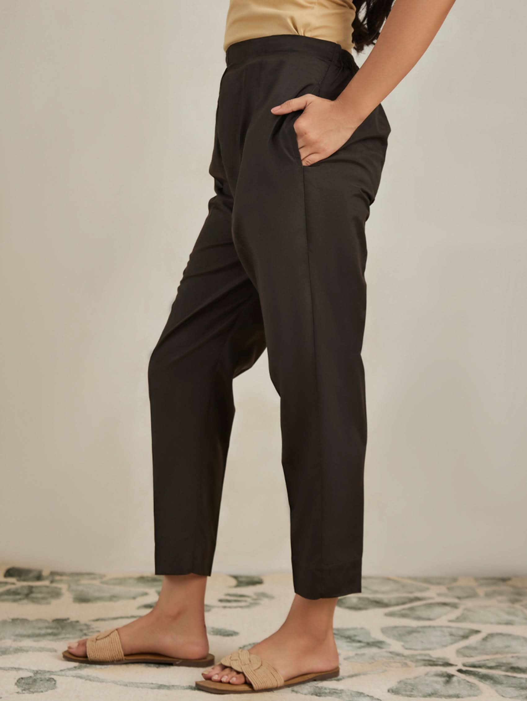 Person wearing black pants standing on a patterned floor with a neutral background